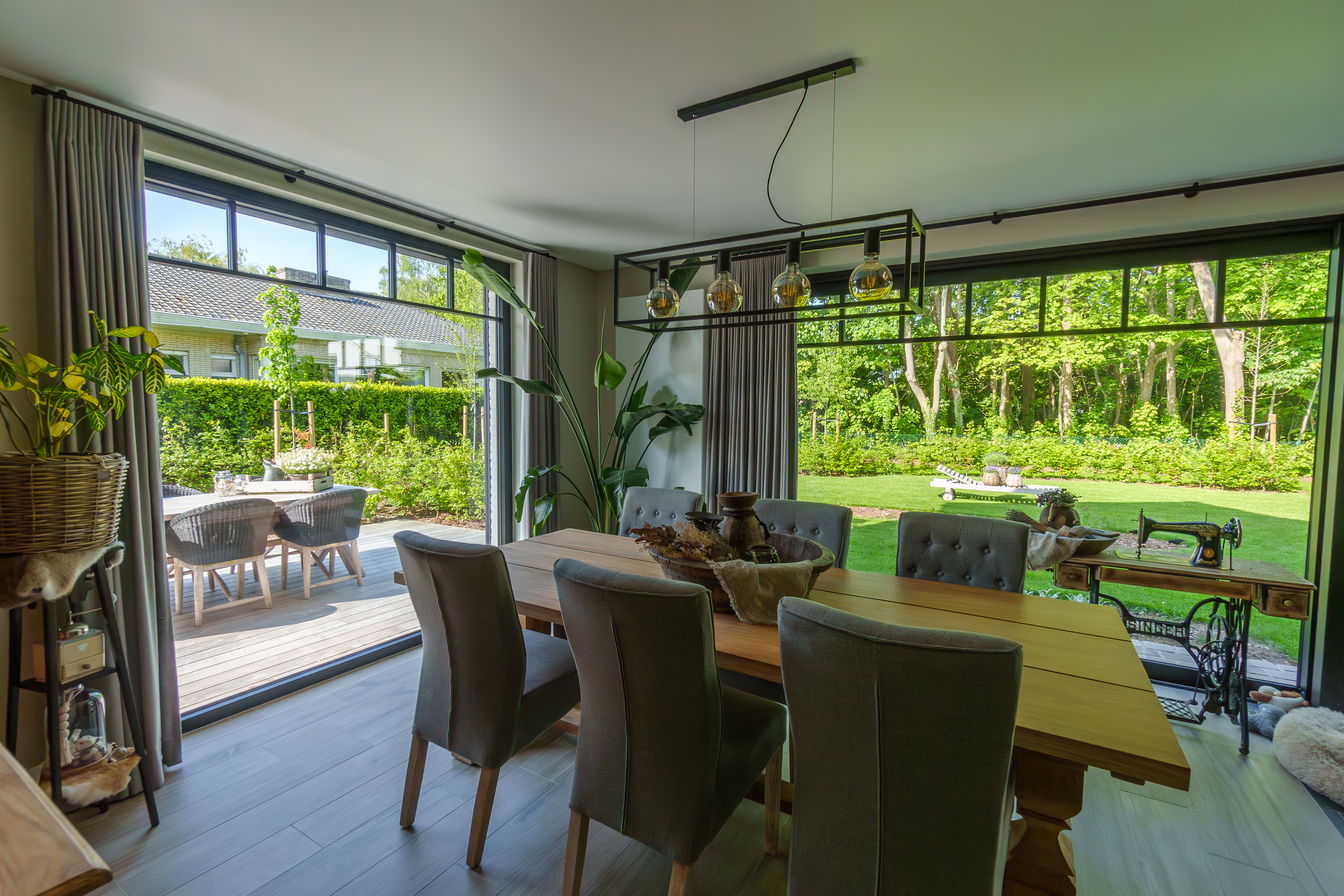 Ruime eetruimte met een matzwart vast raam in een warm landelijk interieur, met uitzicht op de groene omgeving.