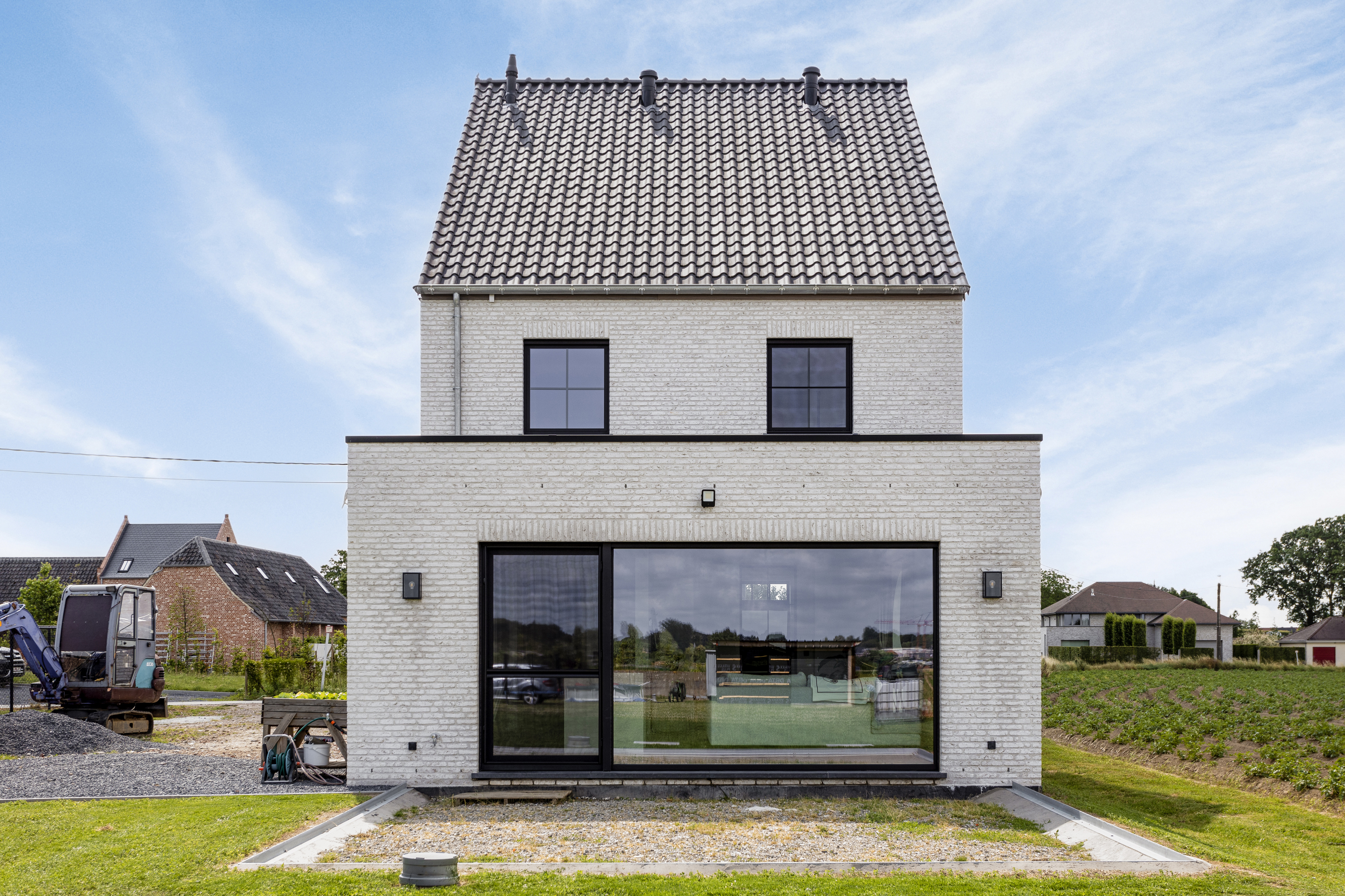 Moderne nieuwbouwwoning in open bebouwing met een groot vast raam in signaalzwart, geïntegreerd in de lichte gevel met een warme landelijke uitstraling.