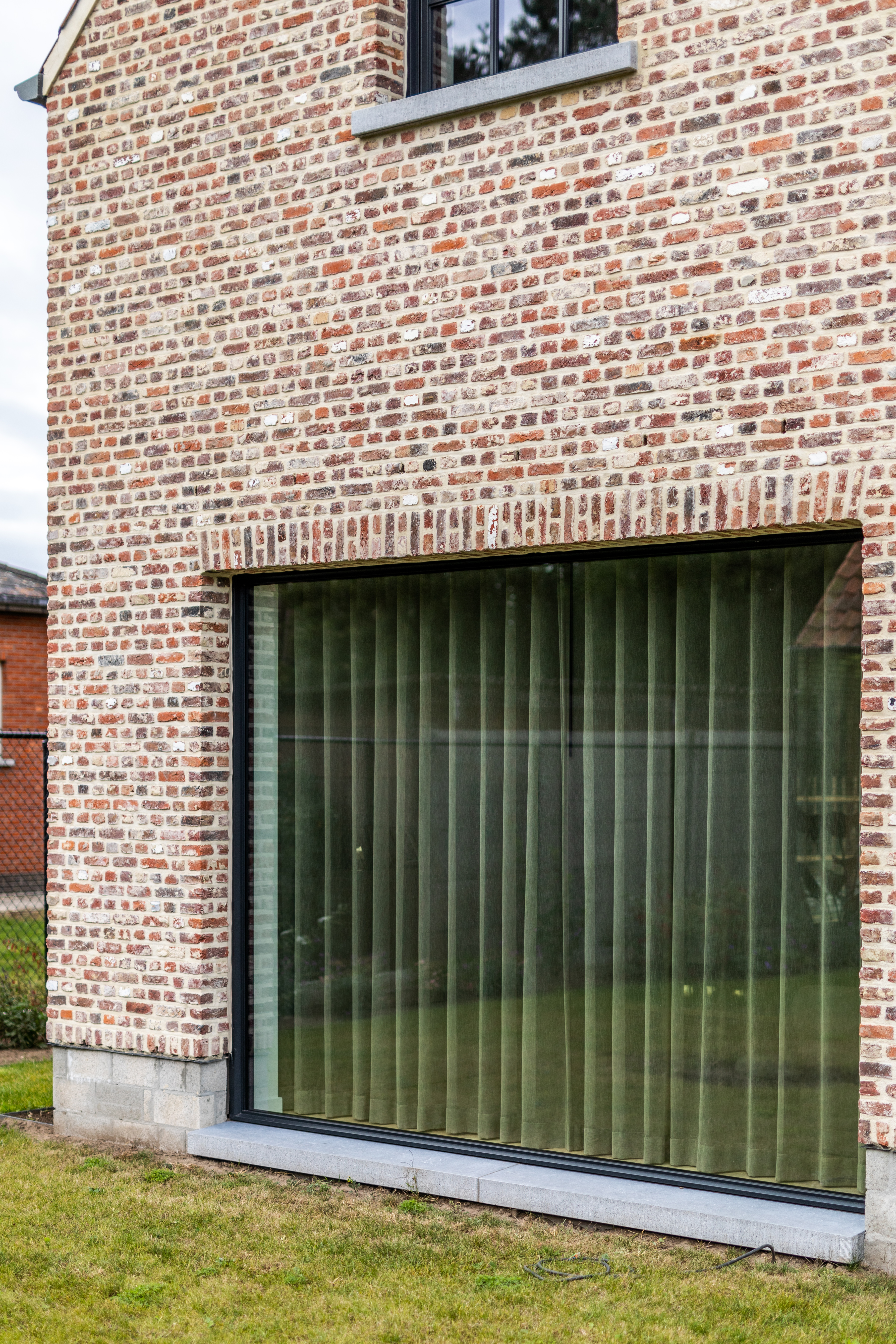 Vast raam met zwarte Steellook PLUS small-profielen in een warme, landelijke bakstenen gevel van een nieuwbouwwoning.