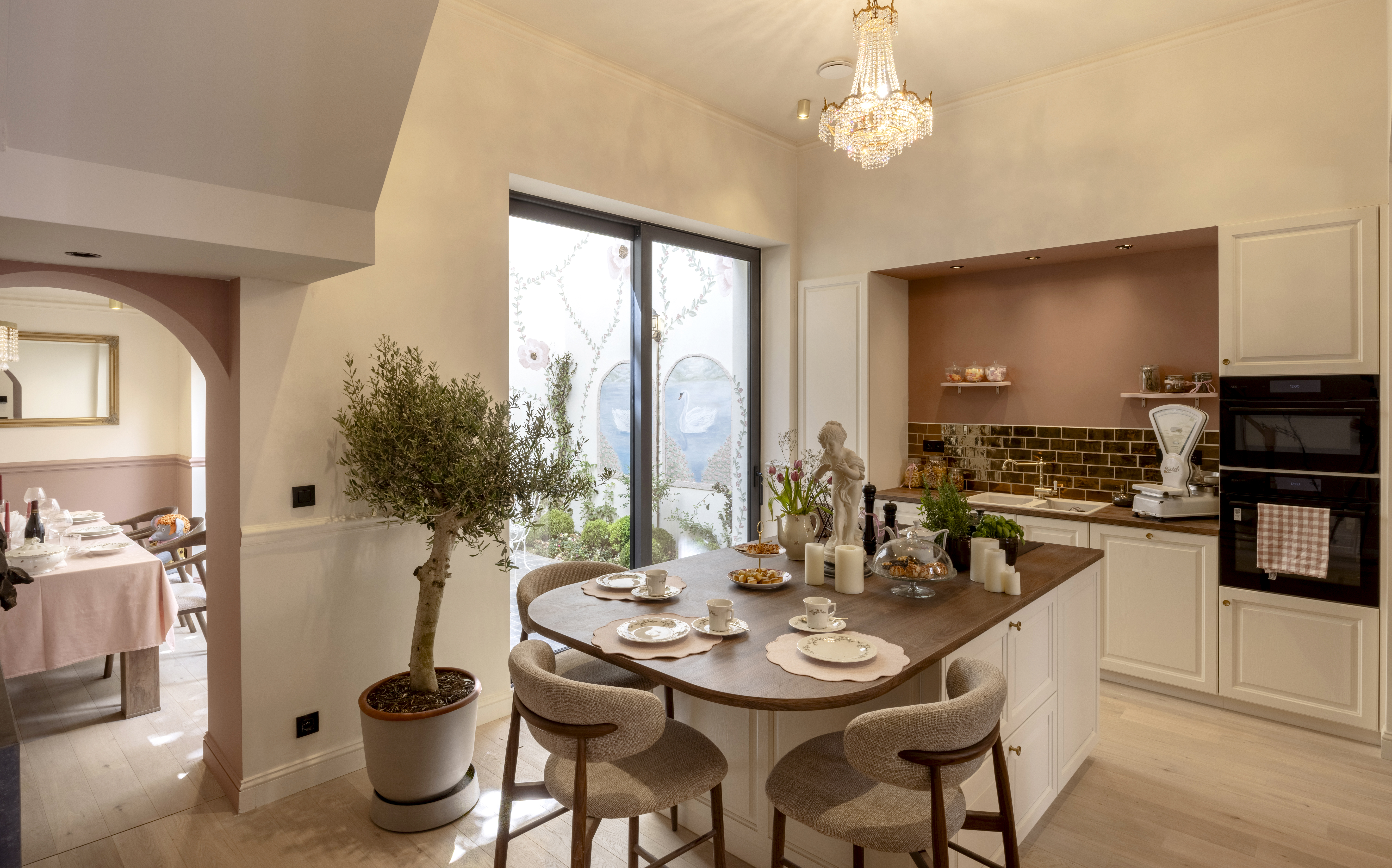 Lichte keuken met eeteiland, donker ALU Visoglide Duorail-schuifraam met matte bronzen afwerking en ingebouwde kasten.