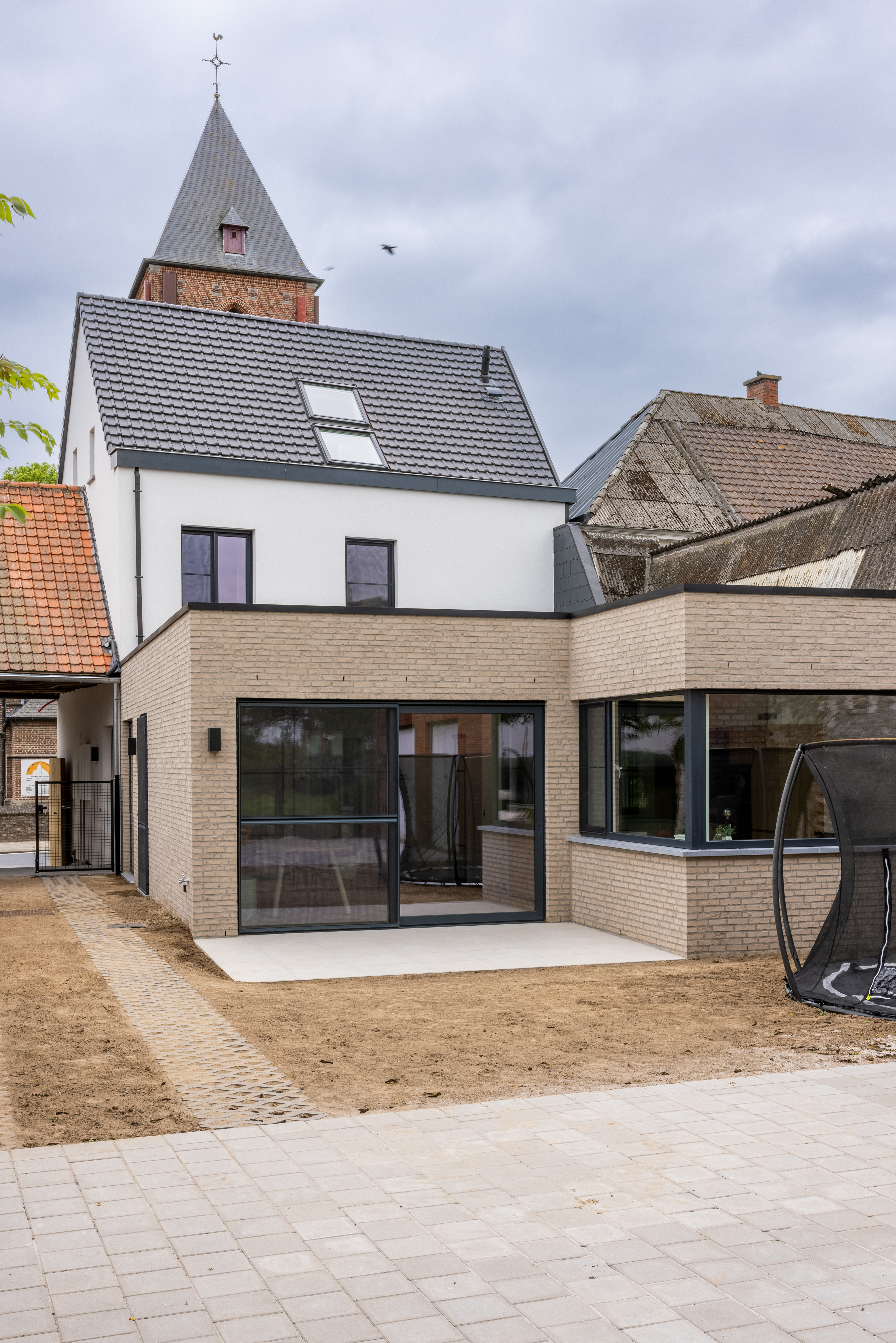 Modern gerenoveerde gesloten bebouwing met antracietgrijze aluminium schuiframen en een schuifvliegenraam op het gelijkvloers.