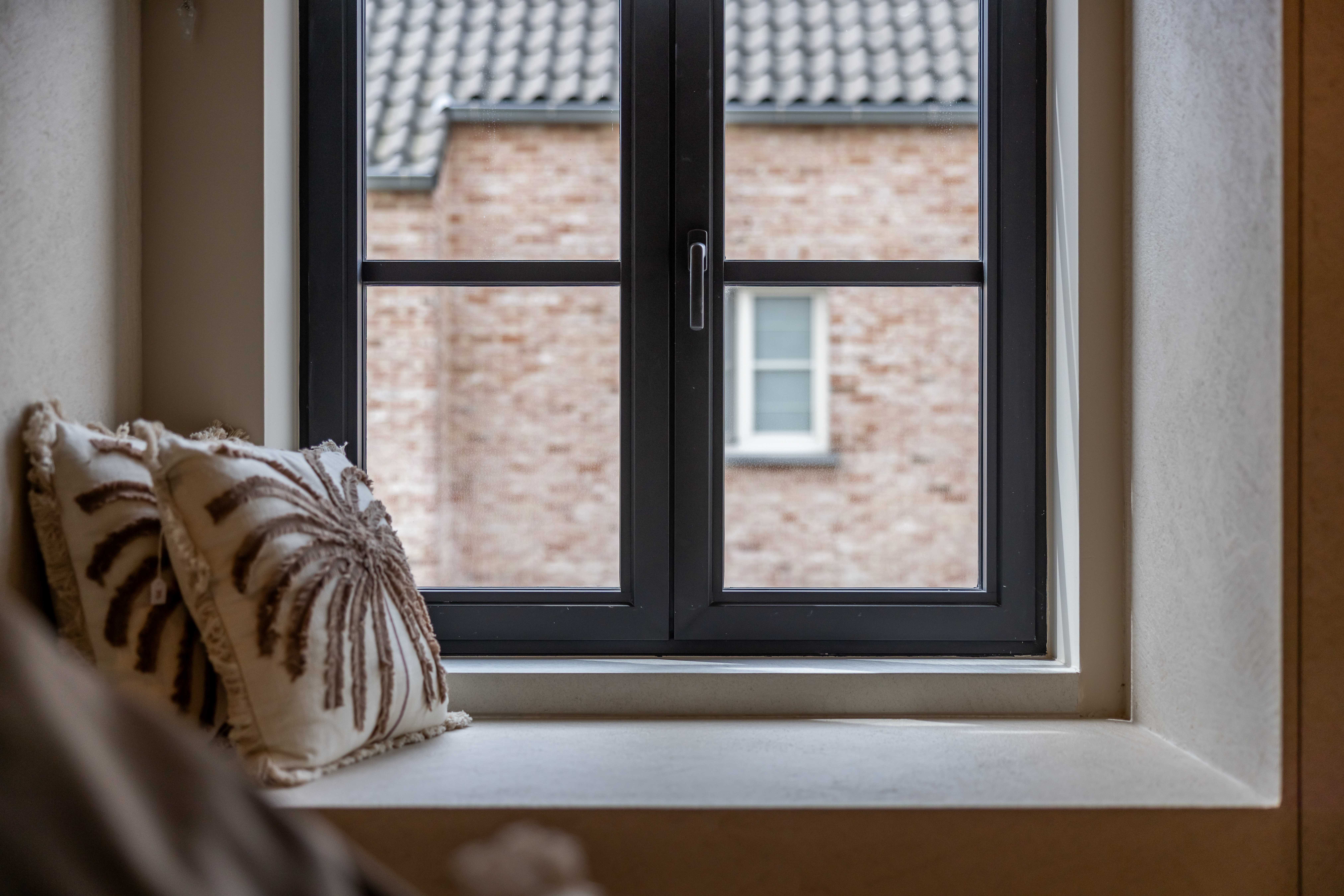 Zwart dubbel draai-kipraam in de smalle Steellook PLUS-stijl van een warm landelijke nieuwbouwwoning, met zicht op een bakstenen gevel.