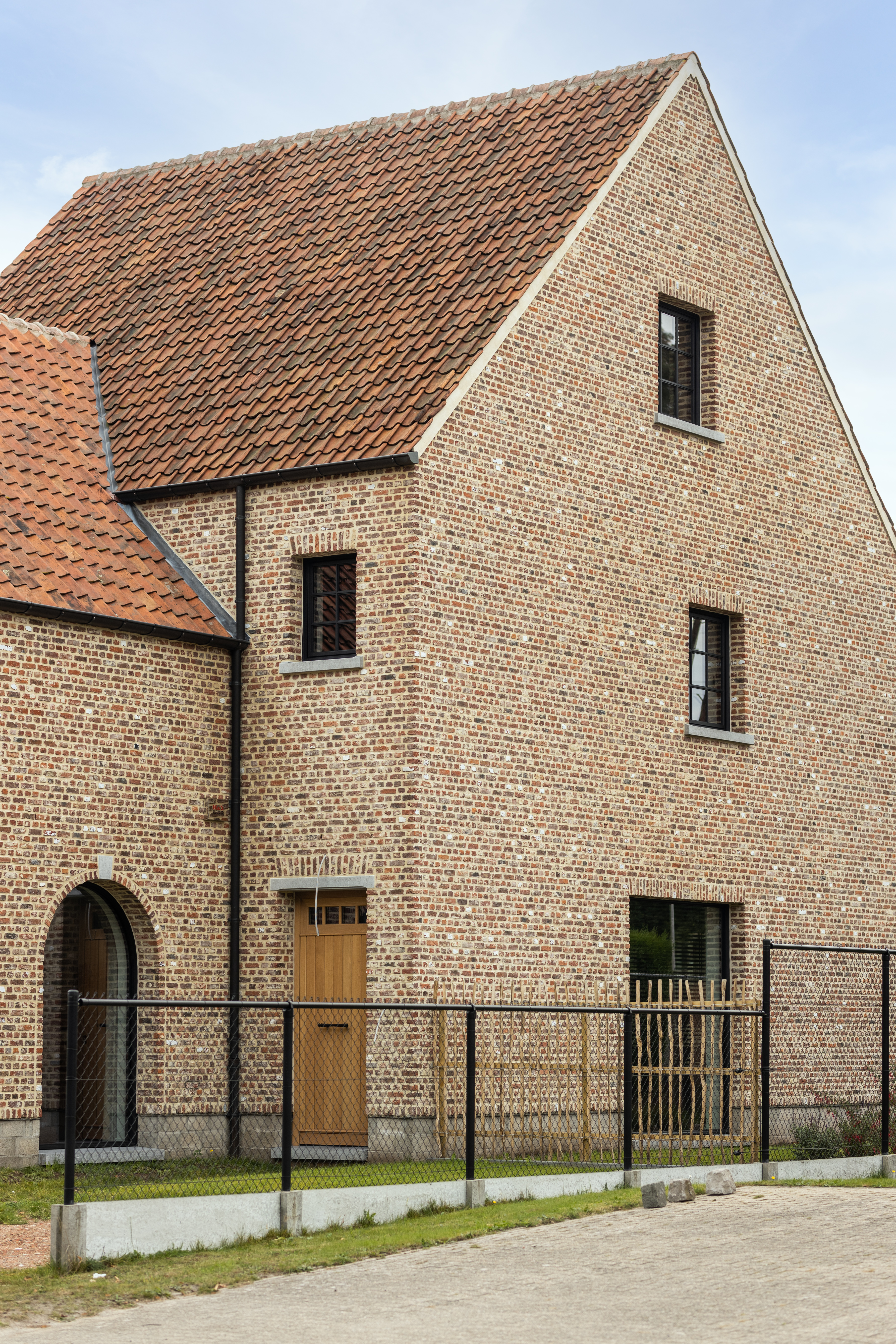 Nieuwbouwwoning in open bebouwing met een warme, landelijke uitstraling, zwarte Steellook-ramen en een deur met bovenlicht in een lichte bakstenen gevel.
