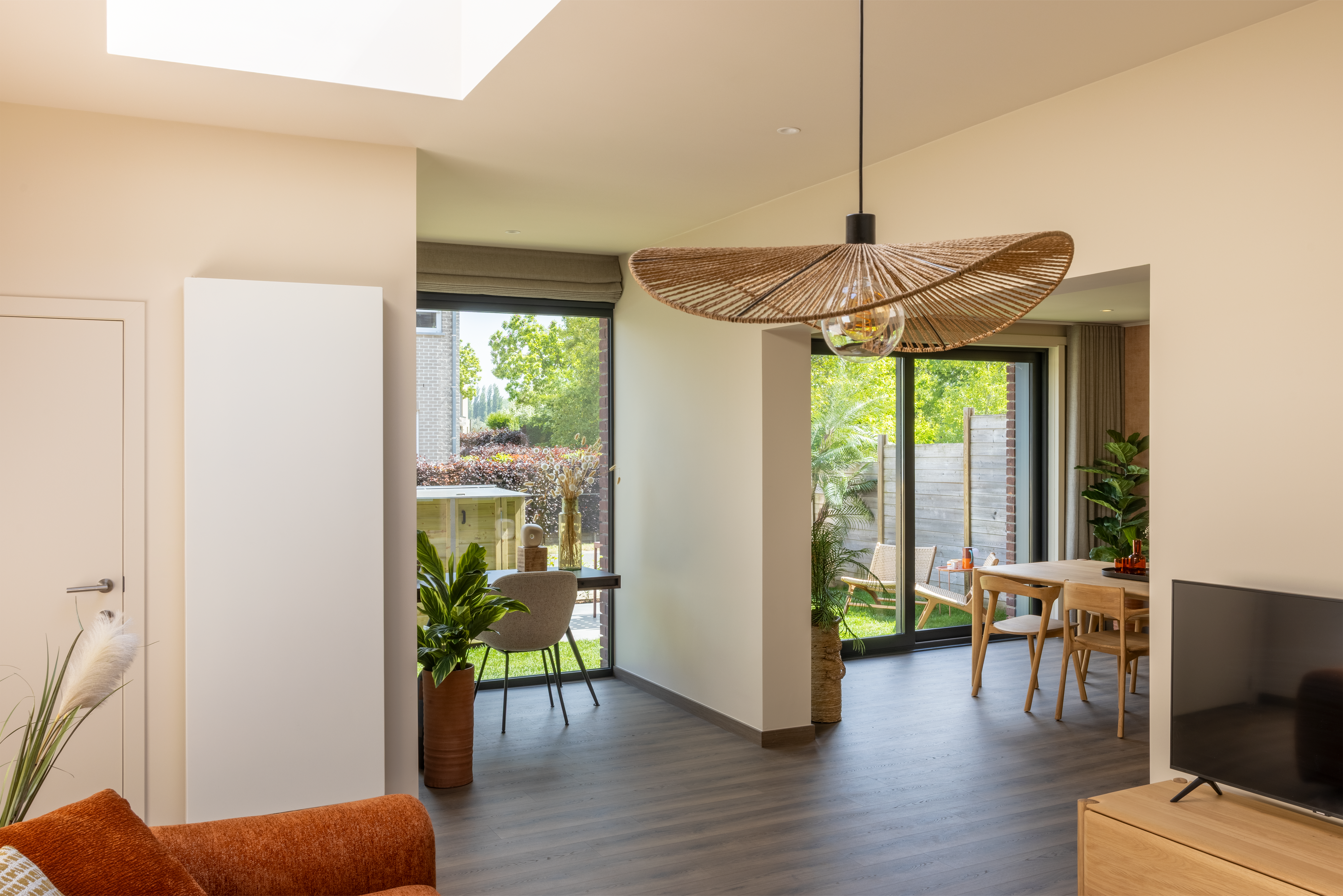Vast raam met antracietgrijze raamprofielen in een gemoedelijk, tijdloos interieur, met zicht op de groene tuin.