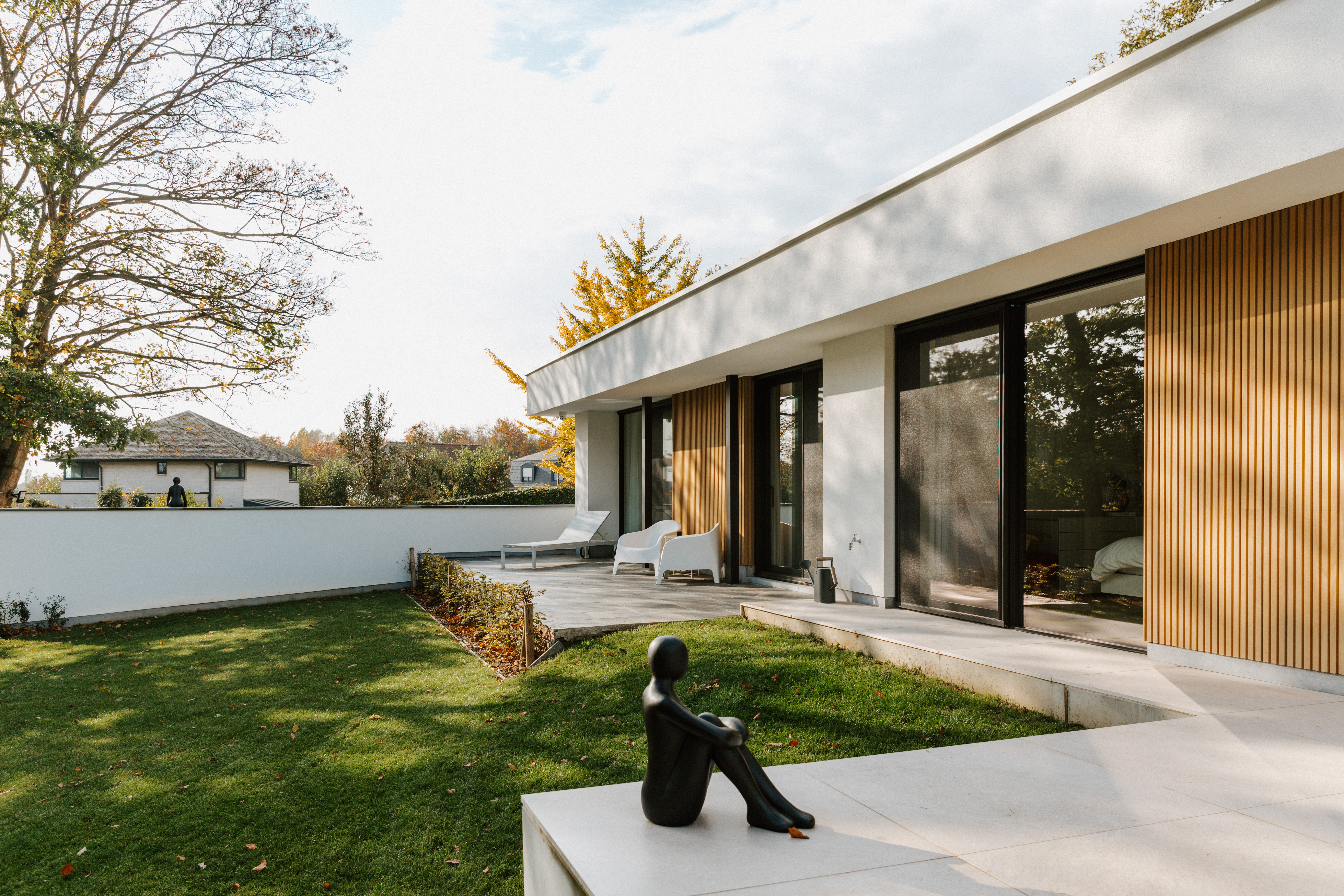 Moderne gerenoveerde woning in open bebouwing met zwarte aluminium schuiframen en een schuifvliegenraam naar het terras en de verzorgde tuin.