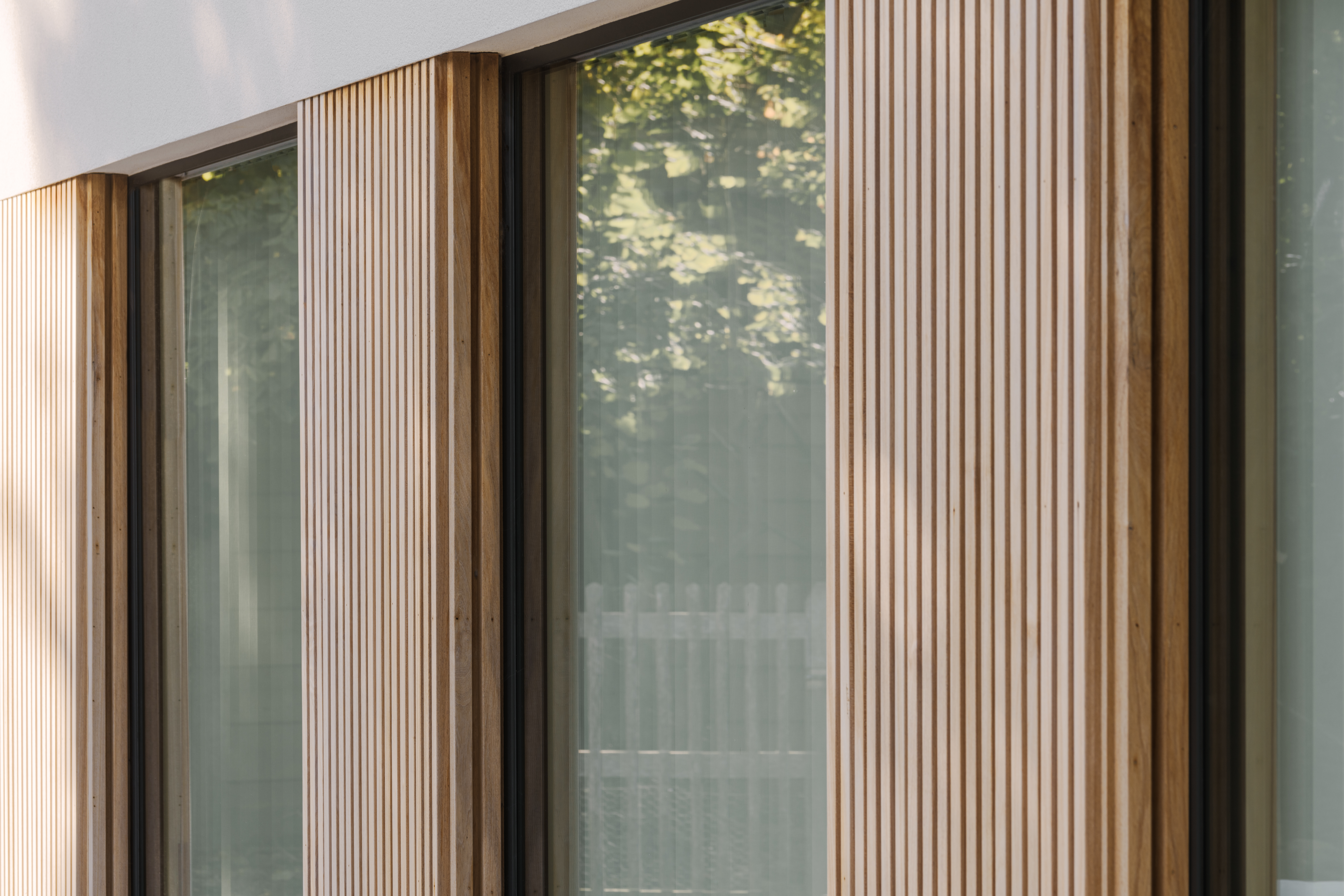 Koncept-vast raam met zwarte 9005TC-profielen in een karaktervolle, moderne houten gevel van een vrijstaande nieuwbouwwoning.