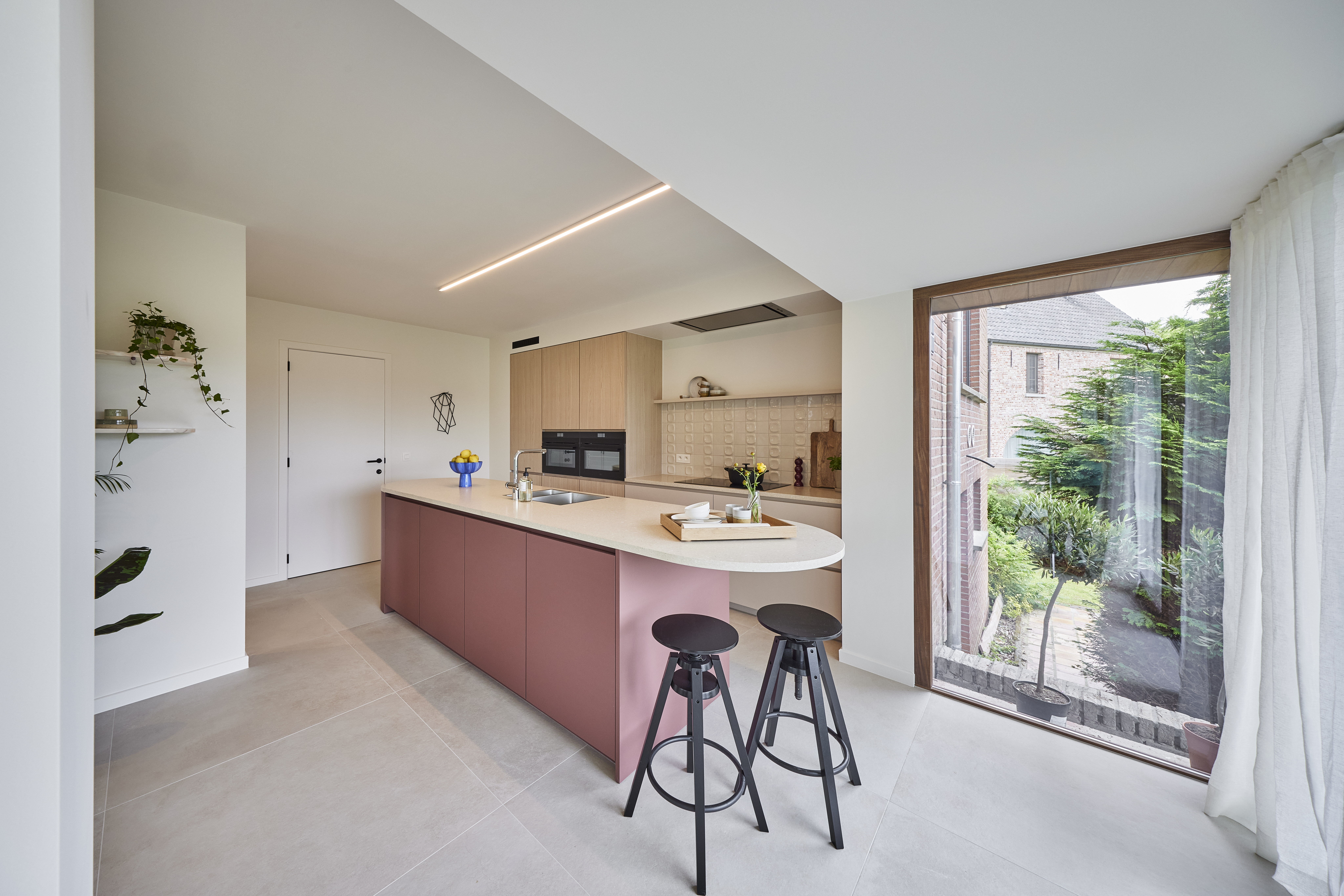 Modern vast raam met Rubio Natural-afwerking naast een open keuken met kookeiland en zicht op een groene binnenkoer.