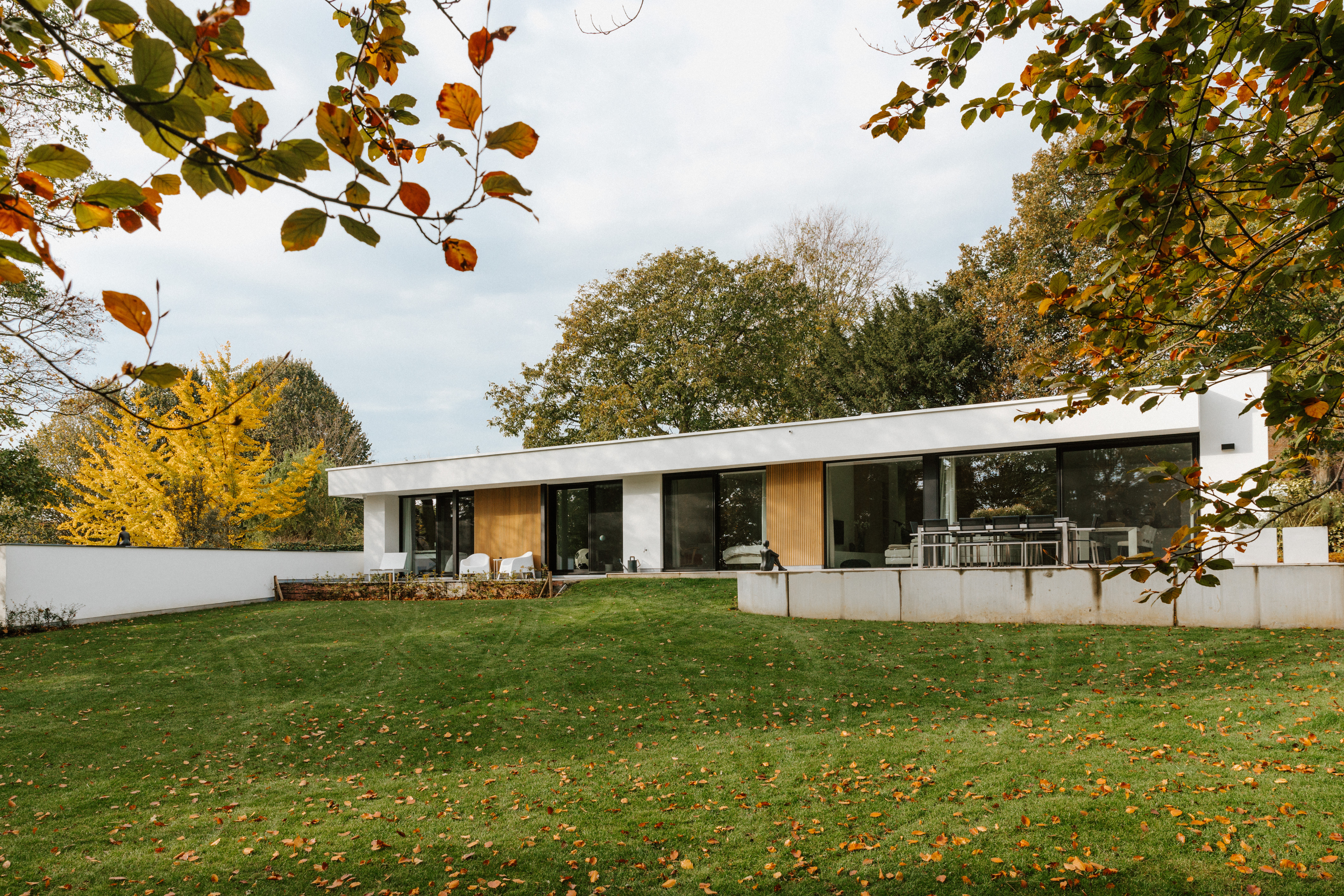Modern gerenoveerde vrijstaande woning met een groot vast raam in zwart aluminium en Visoglide Monorail-schuifelementen uit de Koncept PLUS-reeks, in een ruime tuin.