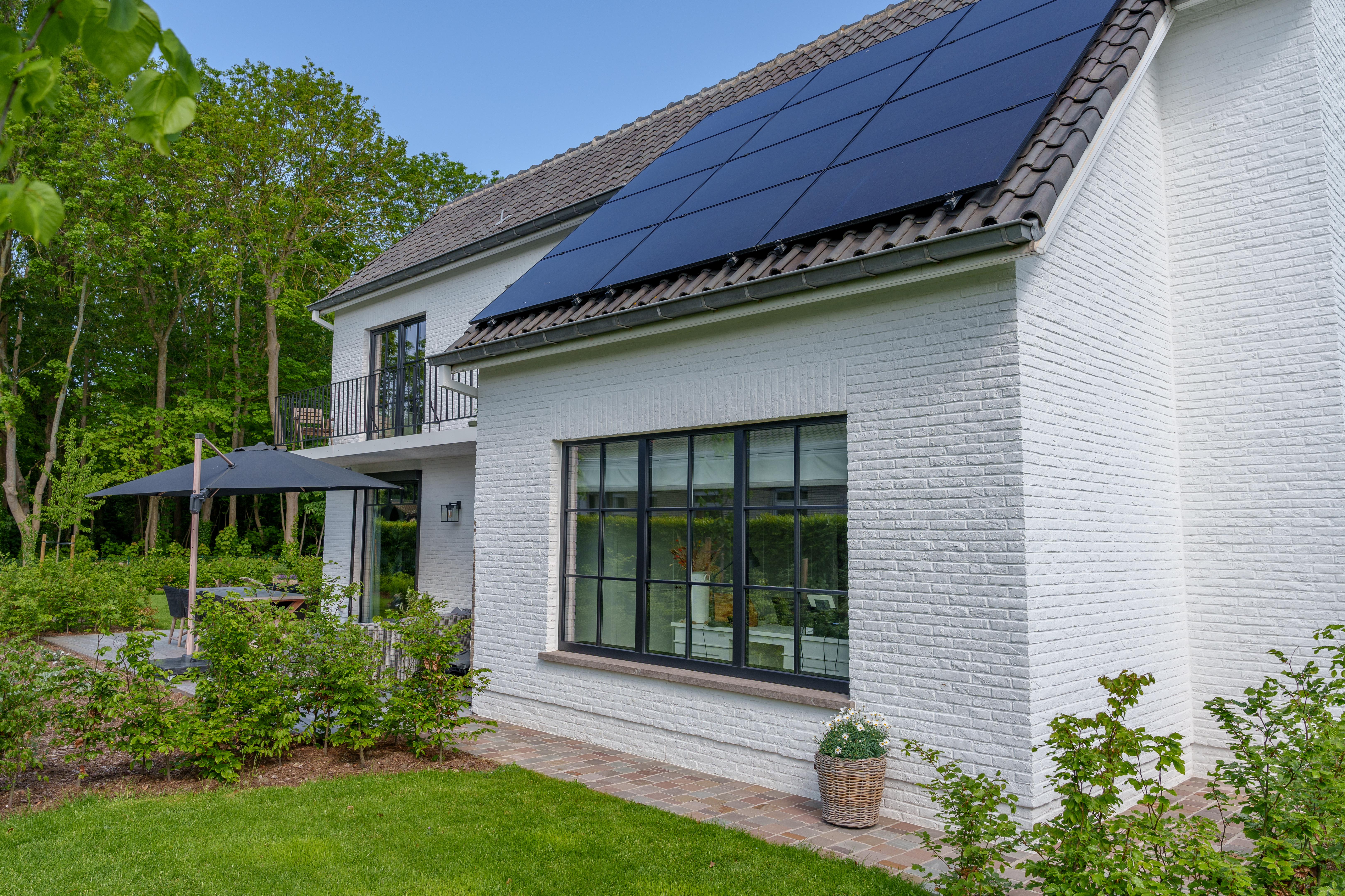 Zwart mat driedubbel raam in een witte bakstenen gevel van een vrijstaande woning, passend bij de warme landelijke stijl van deze renovatie.
