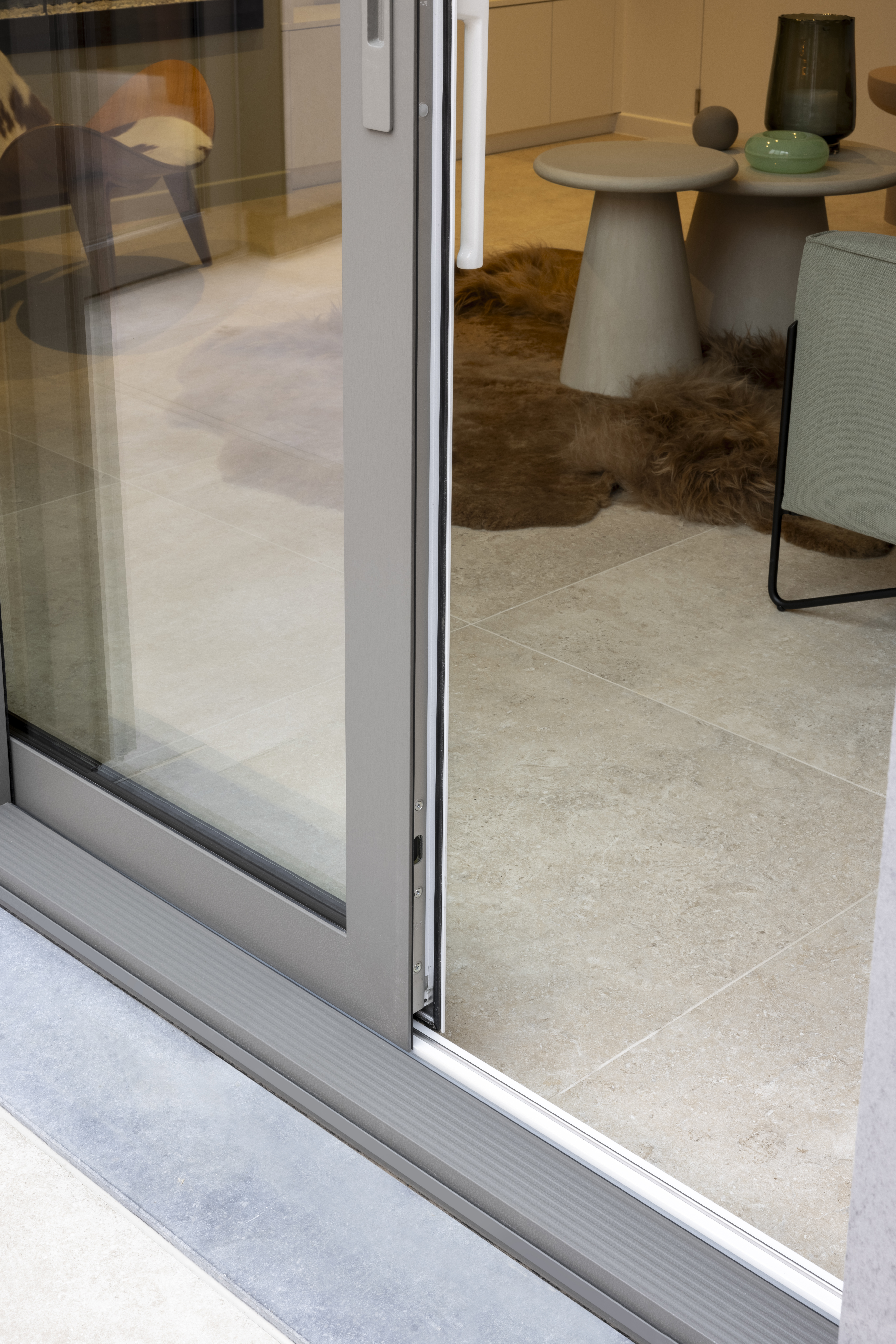 Kwartsgrijs aluminium schuifraam met Visoglide Monorail-profiel in een modern gerenoveerd interieur met een tafel en stoelen.
