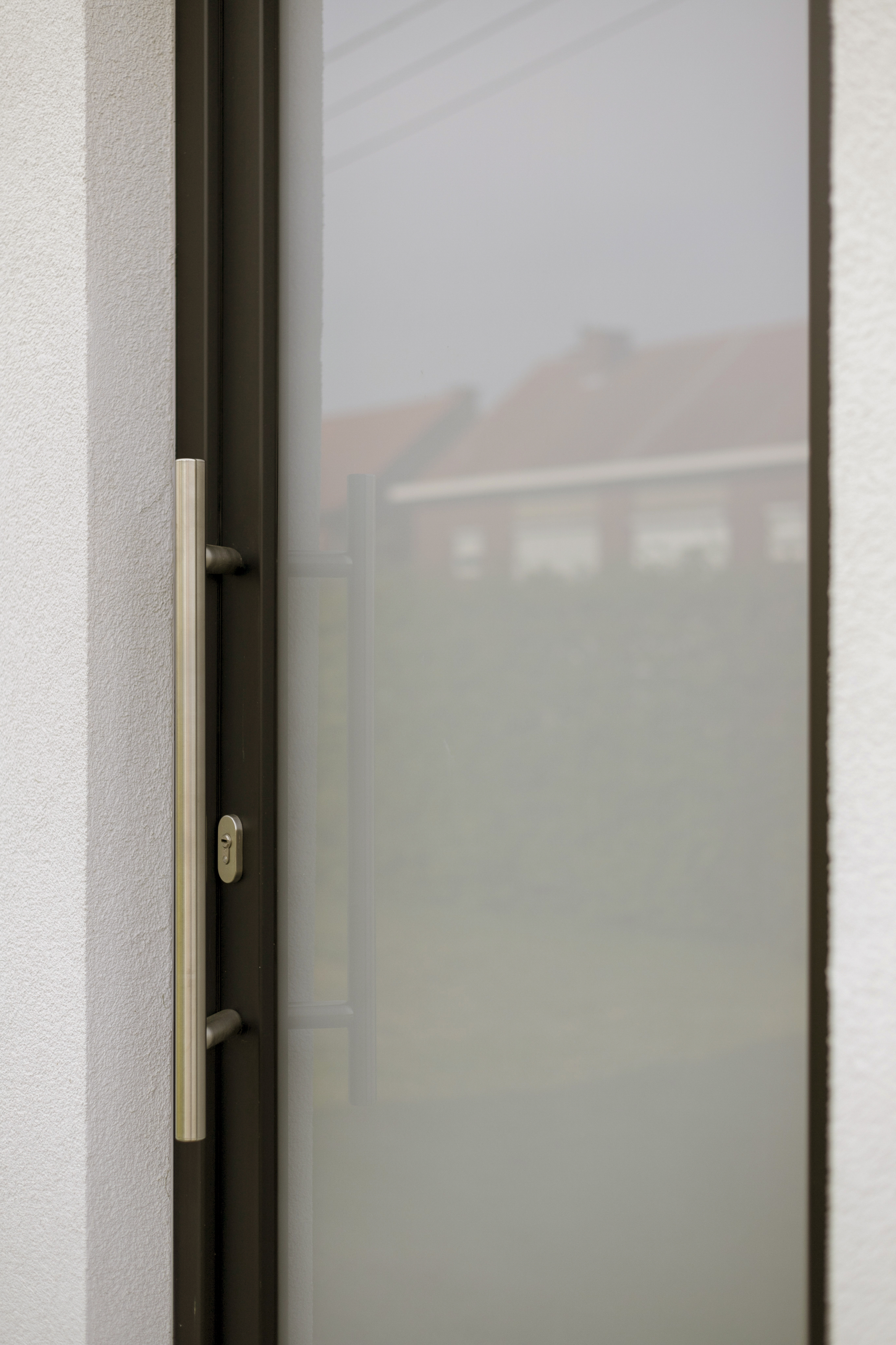 Close-up van een matzwarte PVC-deur met gesatineerde beglazing, zichtbaar deurbeslag en slot, geplaatst in een lichte wand.