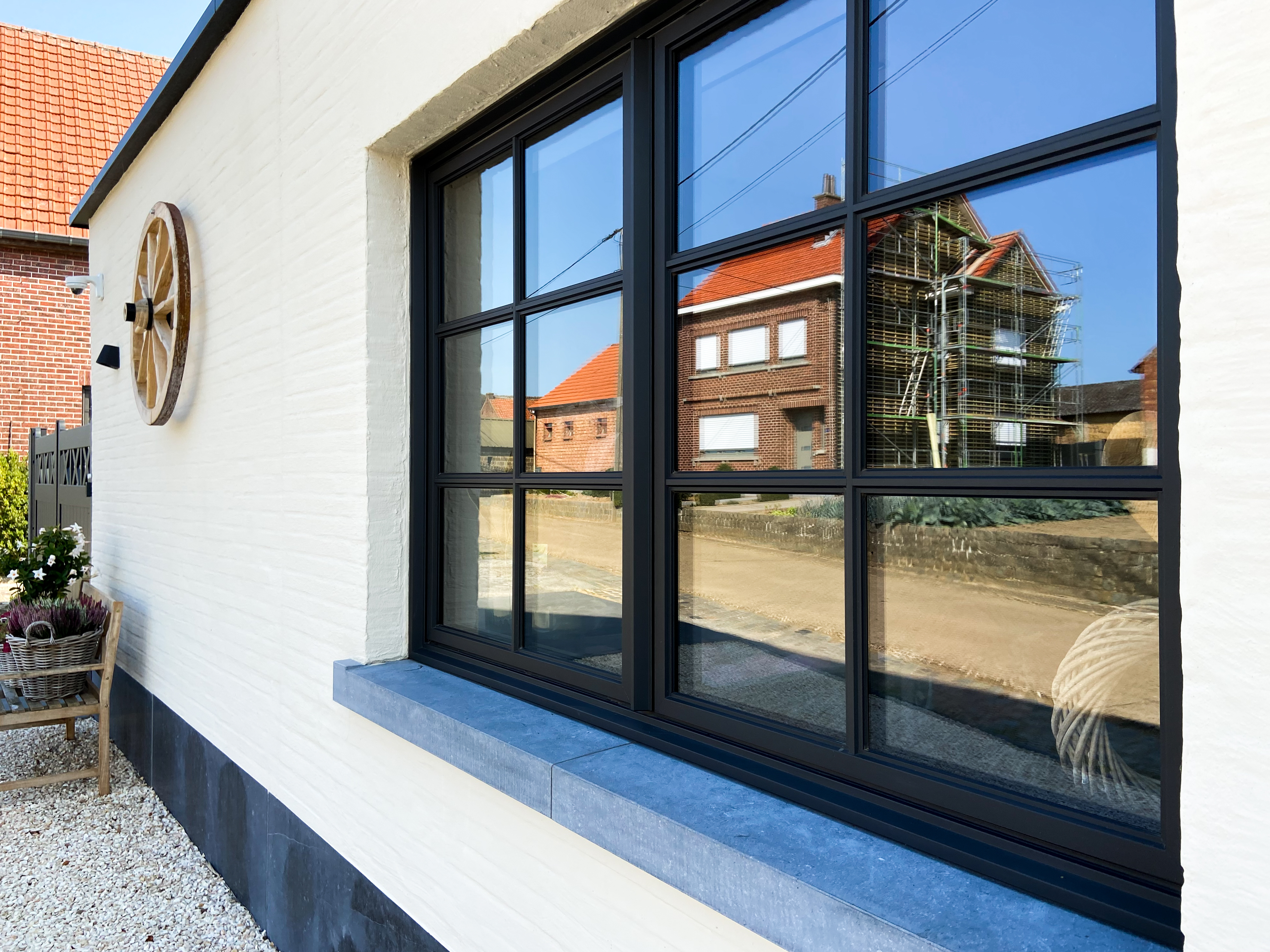 Zwart Steellook PLUS small dubbel raam met draai-kipfunctie in de lichte gevel van een warm landelijk huis tijdens een renovatie.