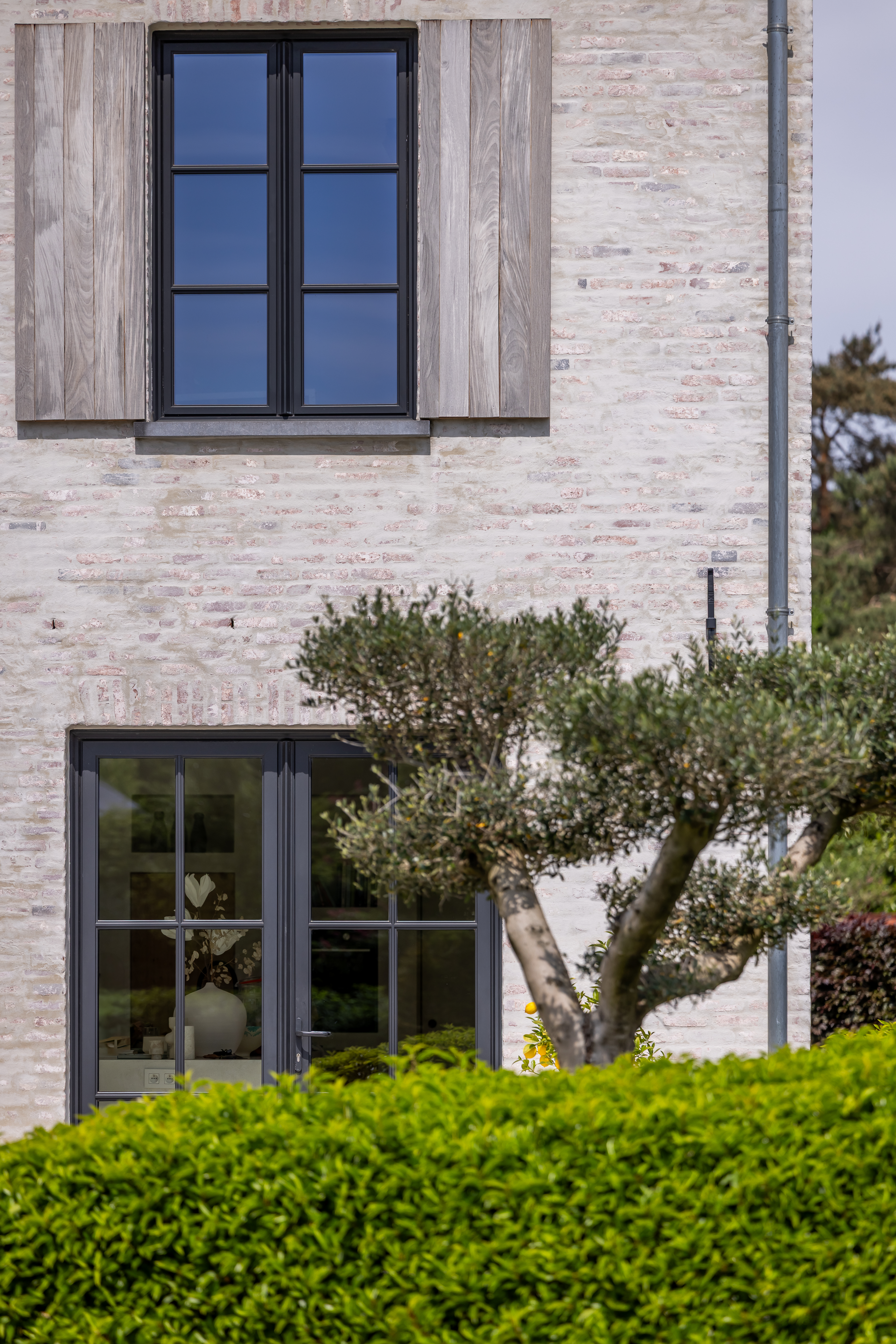 Lichte bakstenen gevel van een vrijstaande nieuwbouwwoning met zwarte Steellook PLUS small-dubbele ramen en een draai-kipraam, passend bij een warme landelijke stijl.