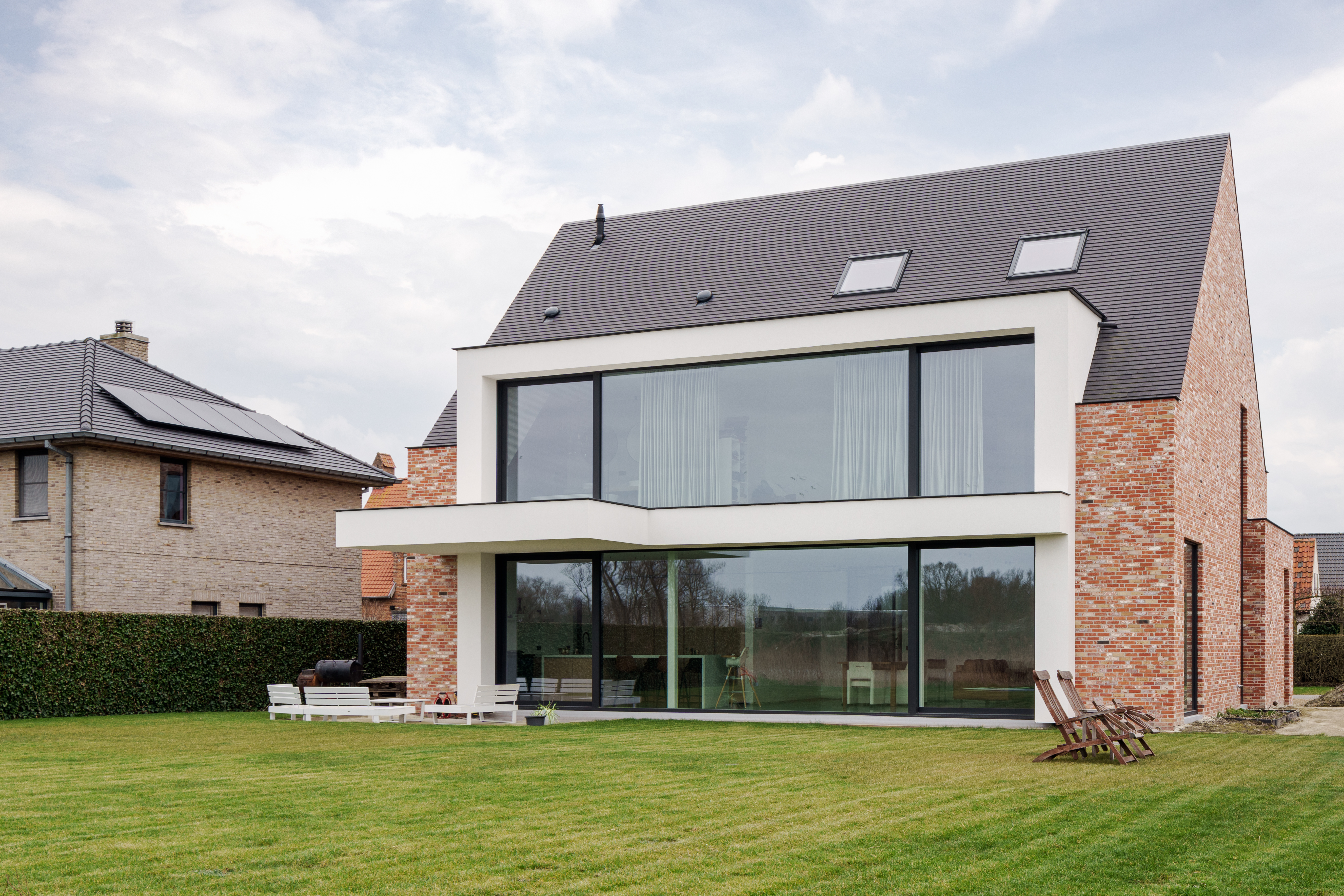 Maison unifamiliale neuve au caractère moderne, avec coulissant en aluminium noir ALU Ultraglide Monorail et grandes baies vitrées côté jardin.