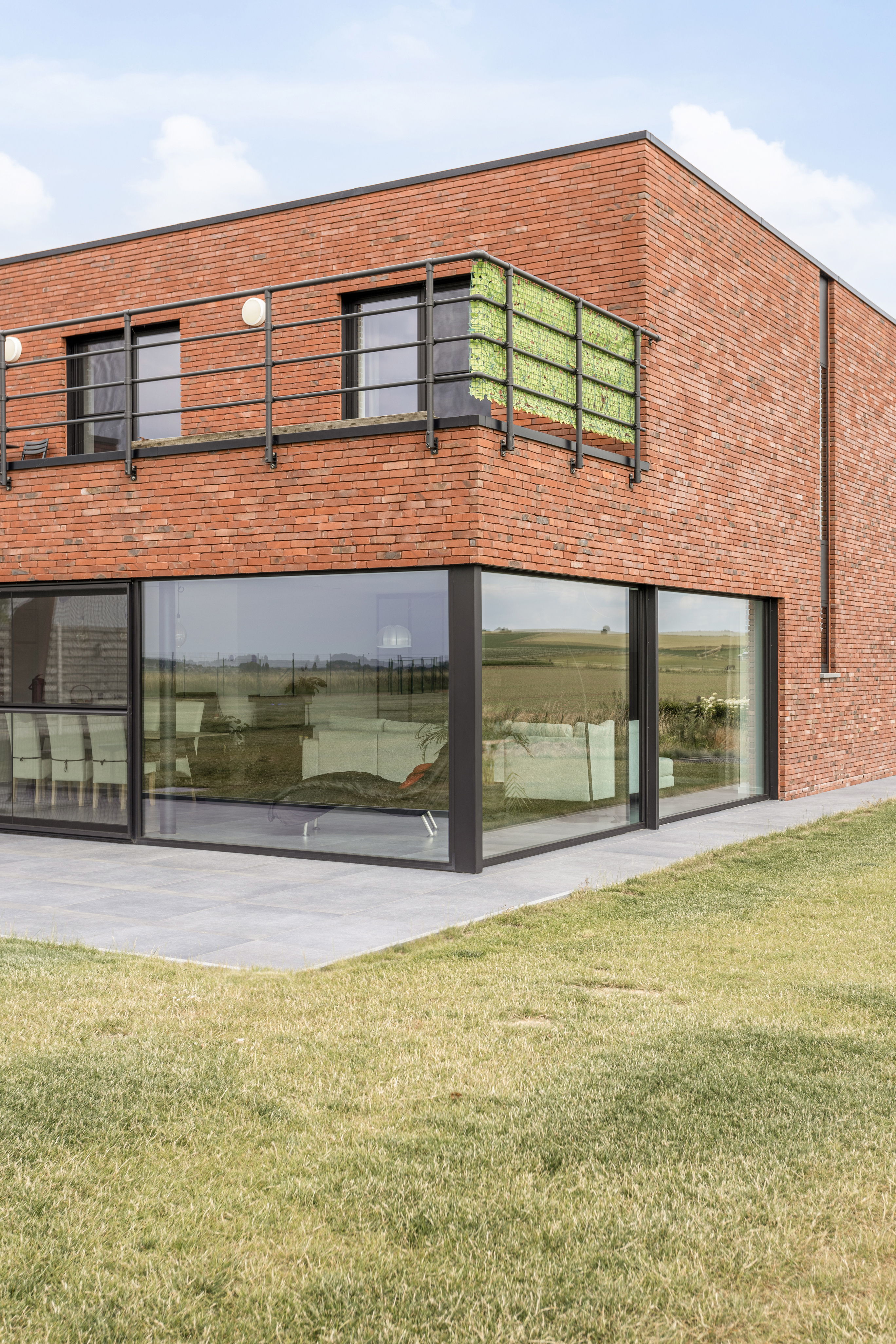 Karaktervolle moderne nieuwbouwwoning in open bebouwing met een bakstenen gevel en grote vaste ramen met zwarte raamprofielen.
