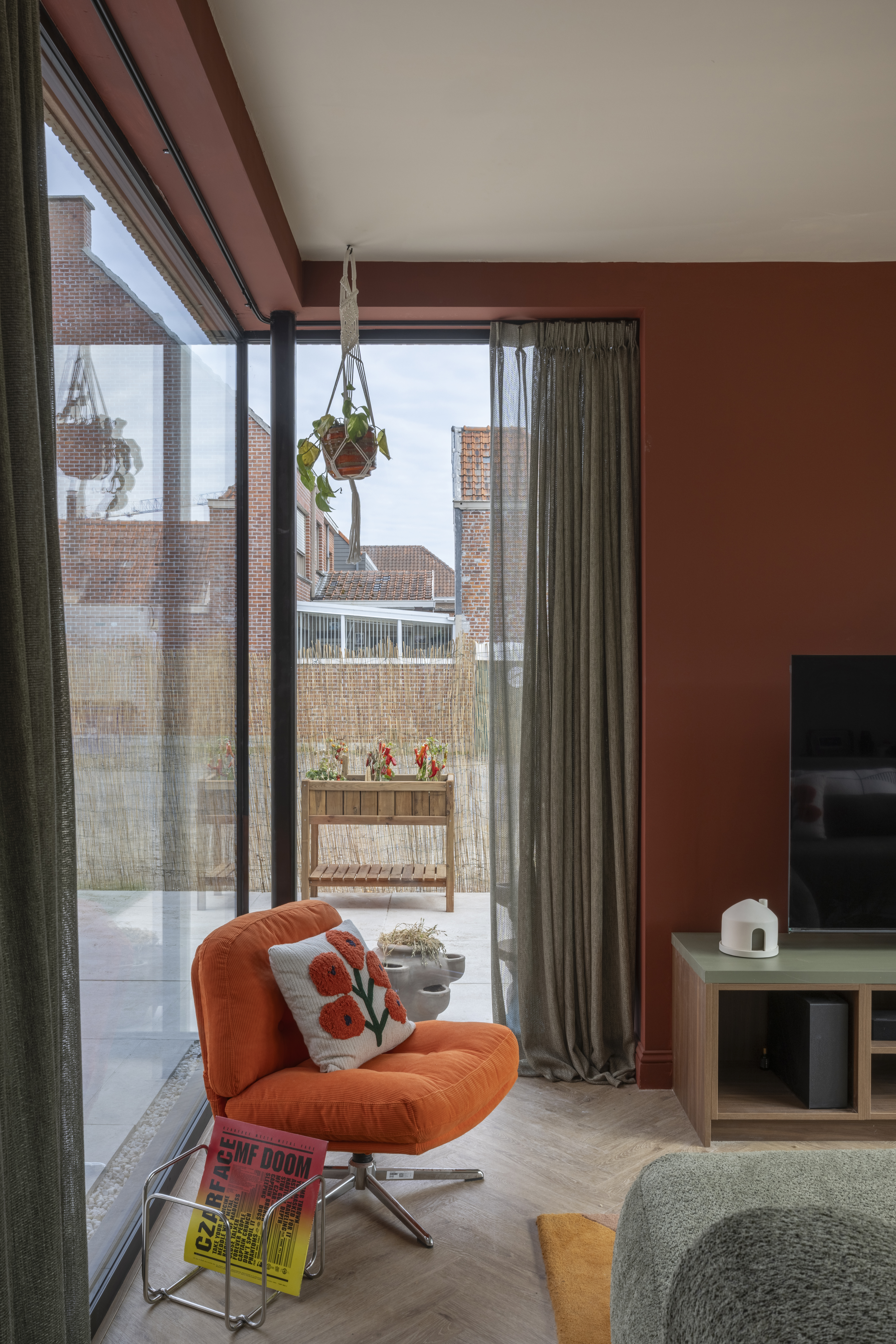 Vast raam met diepzwarte raamprofielen in een woonkamer, van vloer tot plafond, met uitzicht op de omliggende huizen.