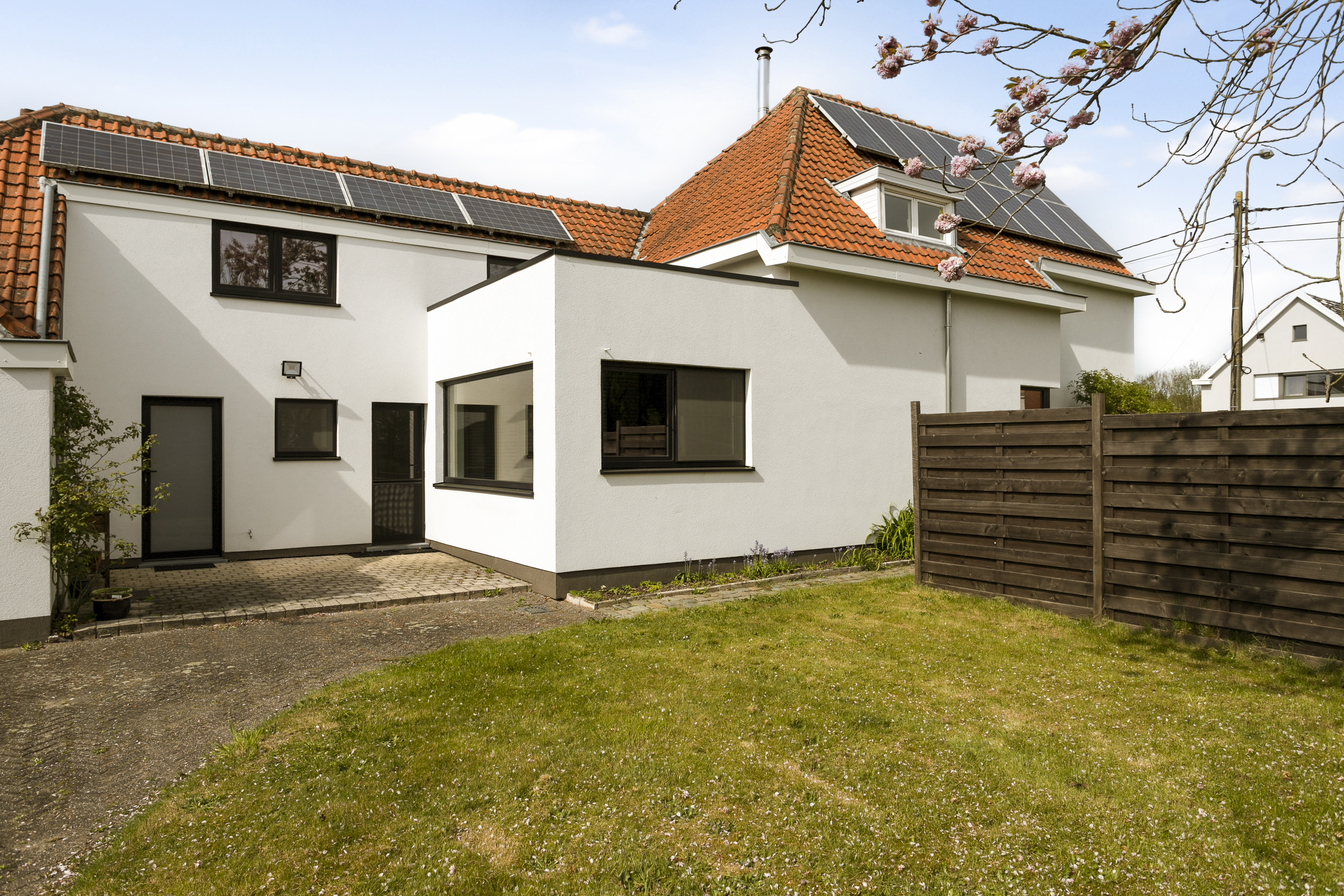 Gerenoveerde vrijstaande woning met witte gevel en matzwarte PVC-ramen: een dubbel raam, draai-kipraam en vast raam naast een beglaasde deur.