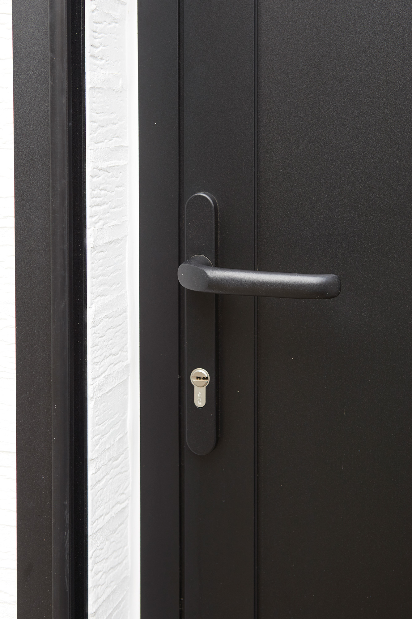 Close-up van een moderne zwarte steellookdeur met sobere deurkruk en sleutelgat, passend bij een eigentijdse renovatie.