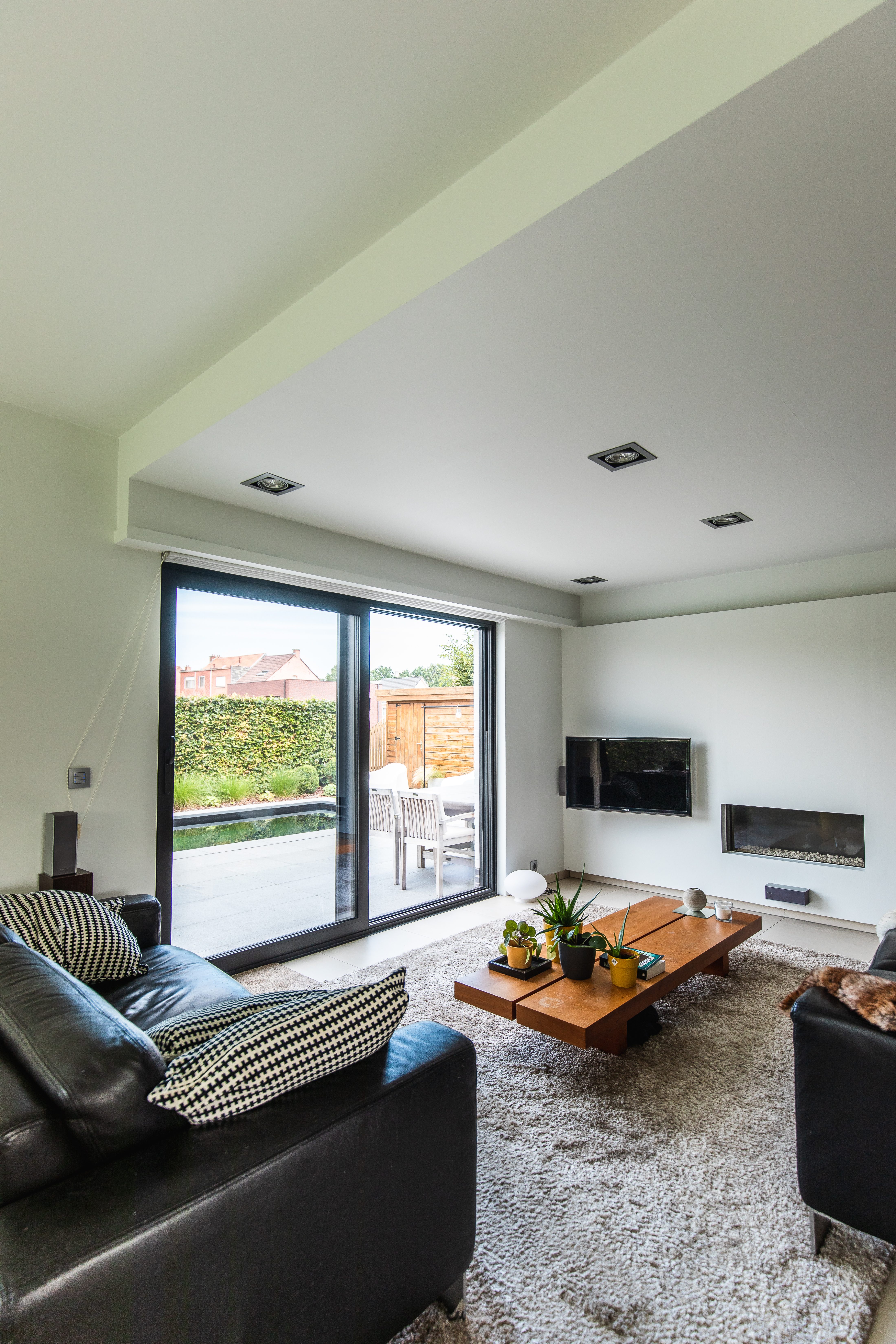 Modern interieur van een gerenoveerde vrijstaande woning met een groot ALU Visoglide Monorail-schuifraam en bijhorend schuifvliegenraam naar het terras.