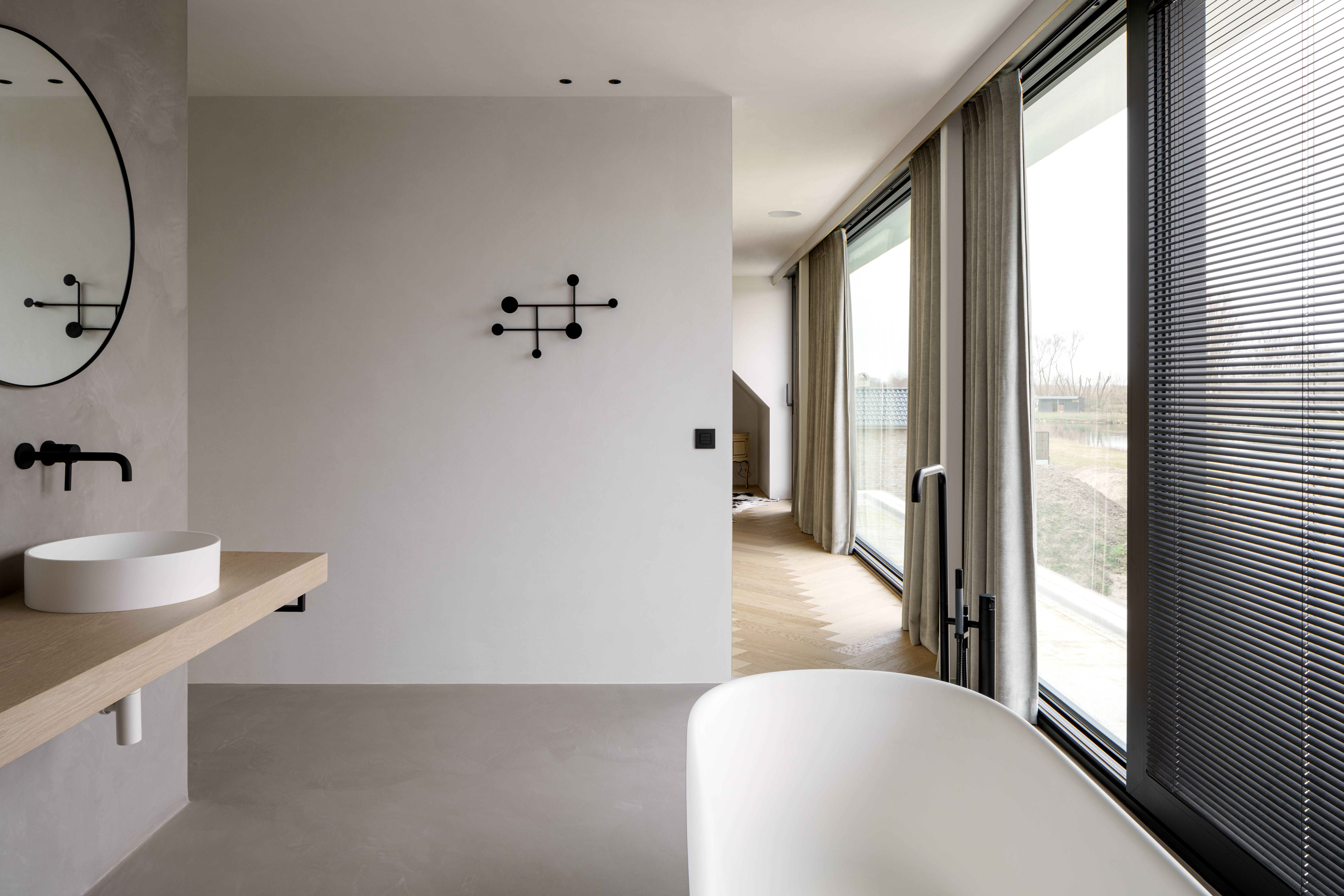 Moderne badkamer met zwart aluminium schuifraam ALU Ultraglide Monorail, kamerhoge beglazing, gordijnen en jaloezieën in een nieuwbouwwoning.