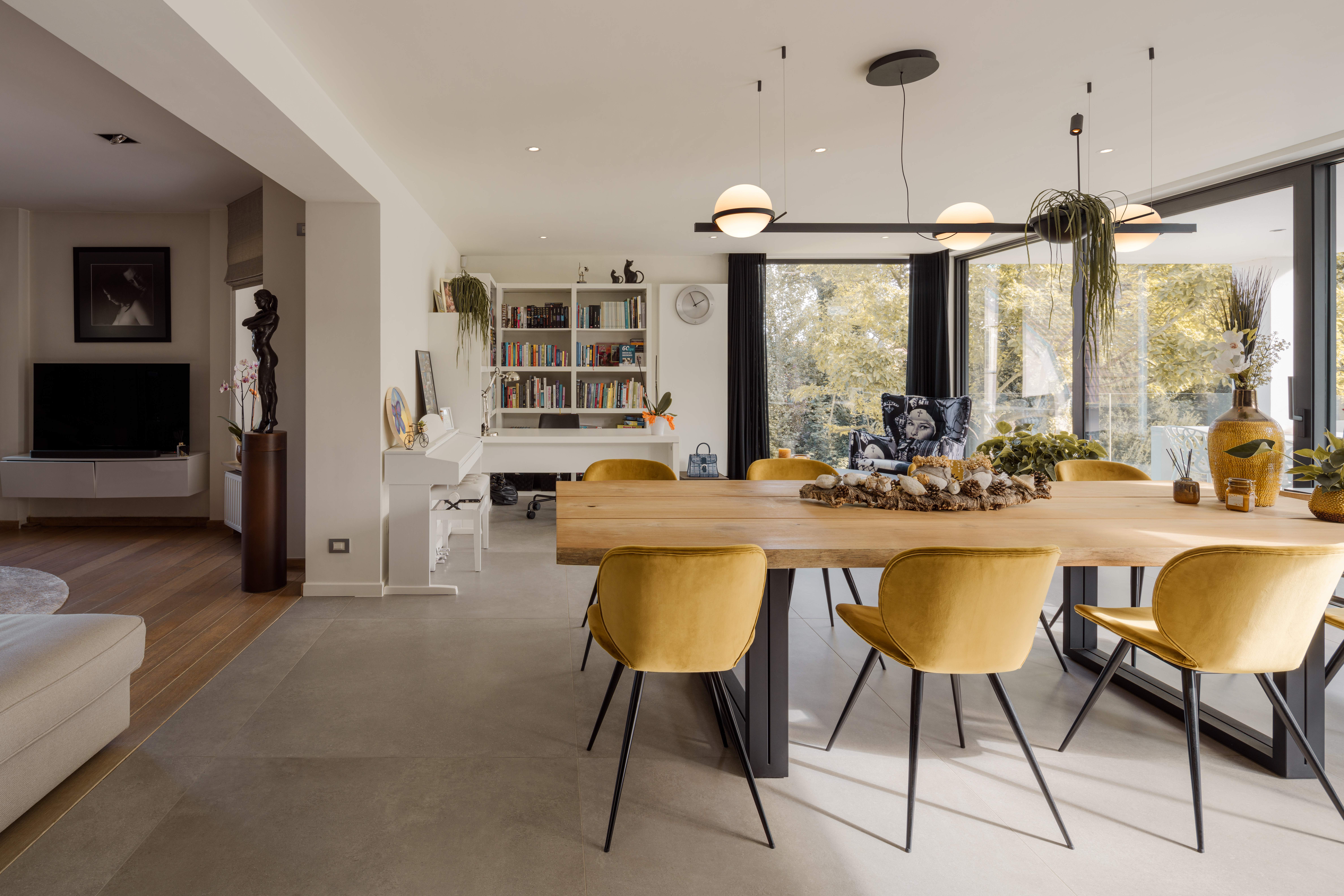 Modern eetgedeelte in een nieuwbouwwoning met zwart ALU Visoglide Monorail-schuifraam, houten tafel en zicht op het groen.