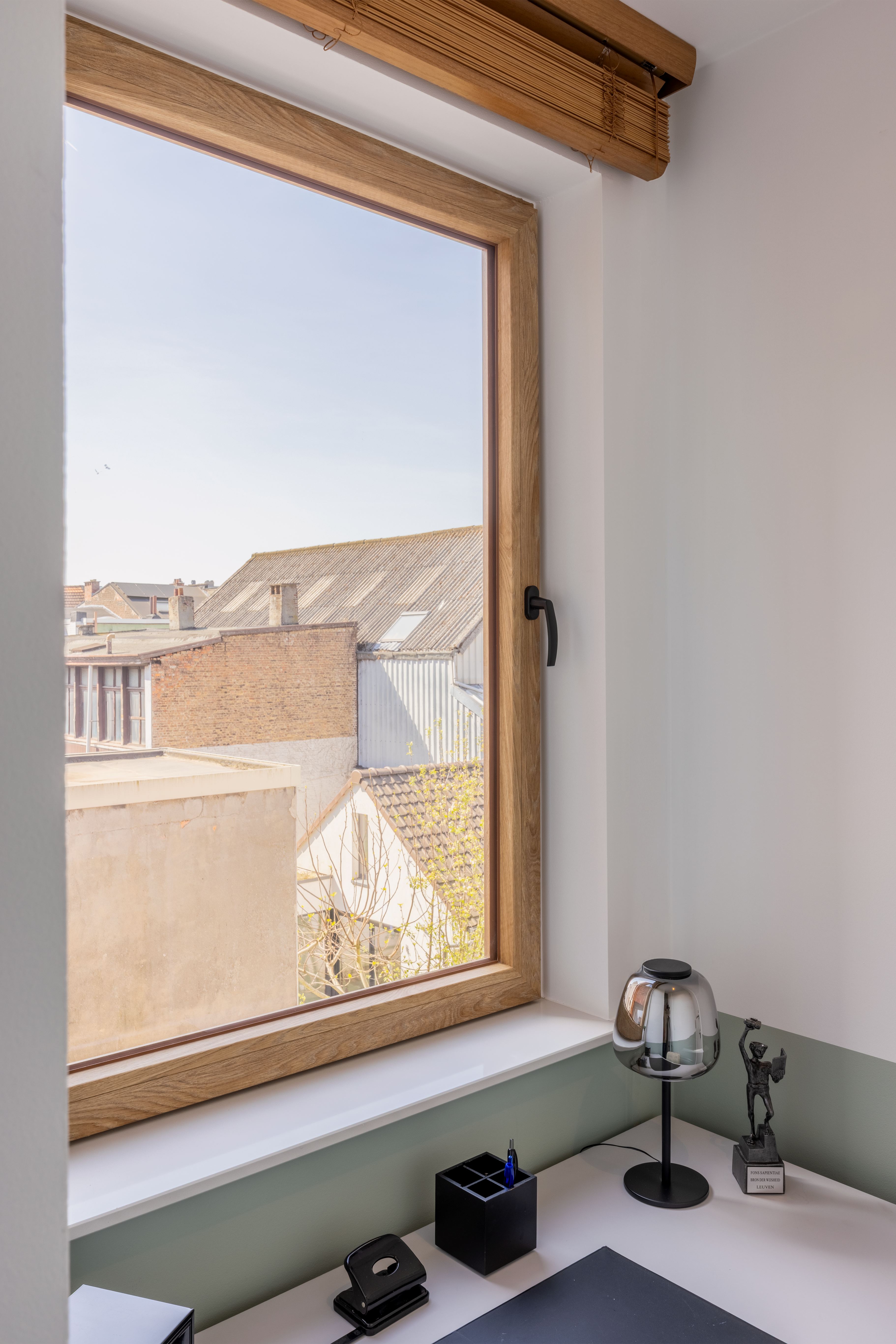 Draai-kipraam met natuurkleurige eiklook en zichtbare nerf in een lichte binnenruimte, met uitzicht op dichtbebouwde aanpalende woningen.