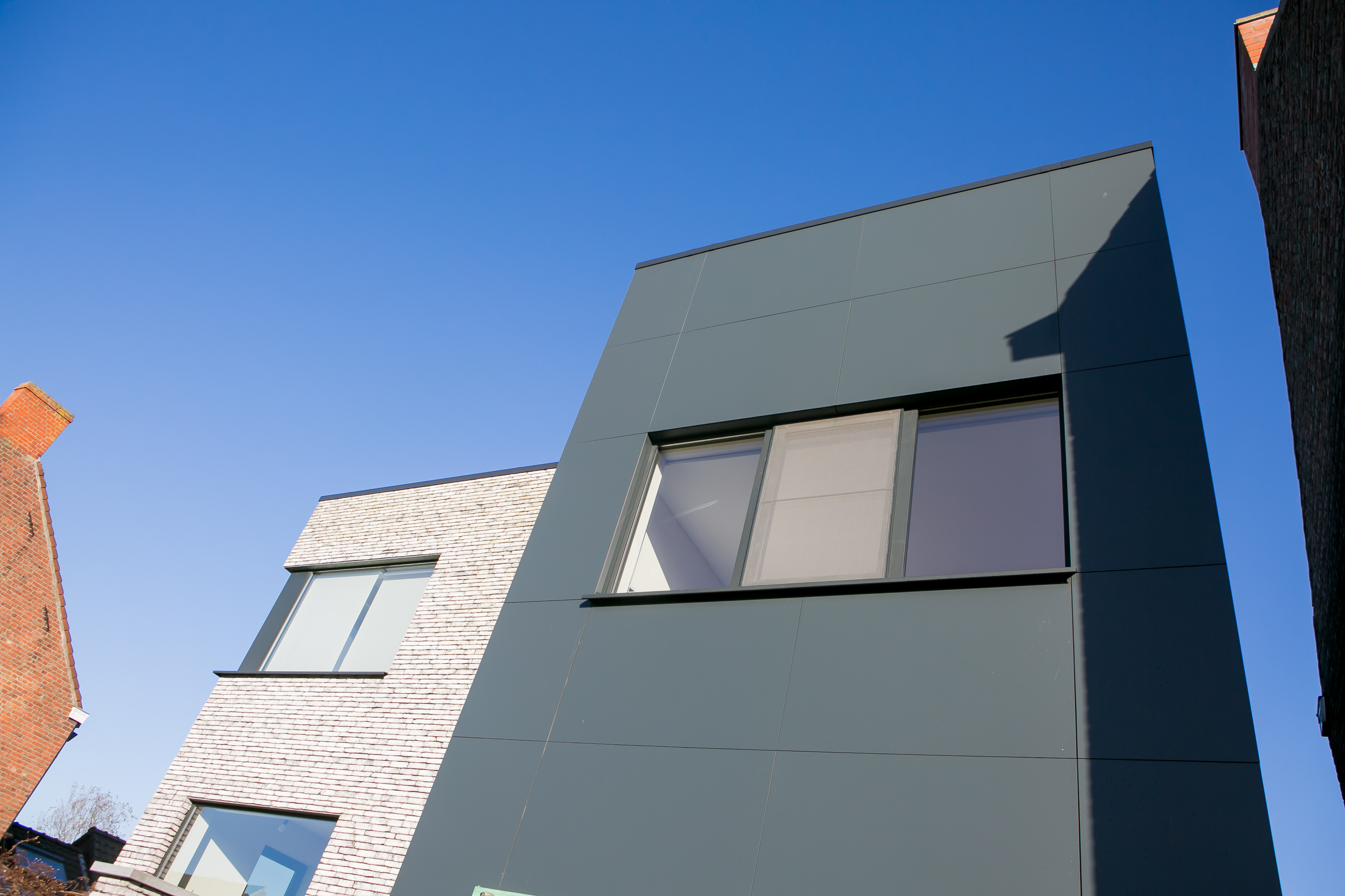 Driedubbel raam in een zwartgrijs raamprofiel in de moderne gevel van een nieuwbouwwoning in open bebouwing.