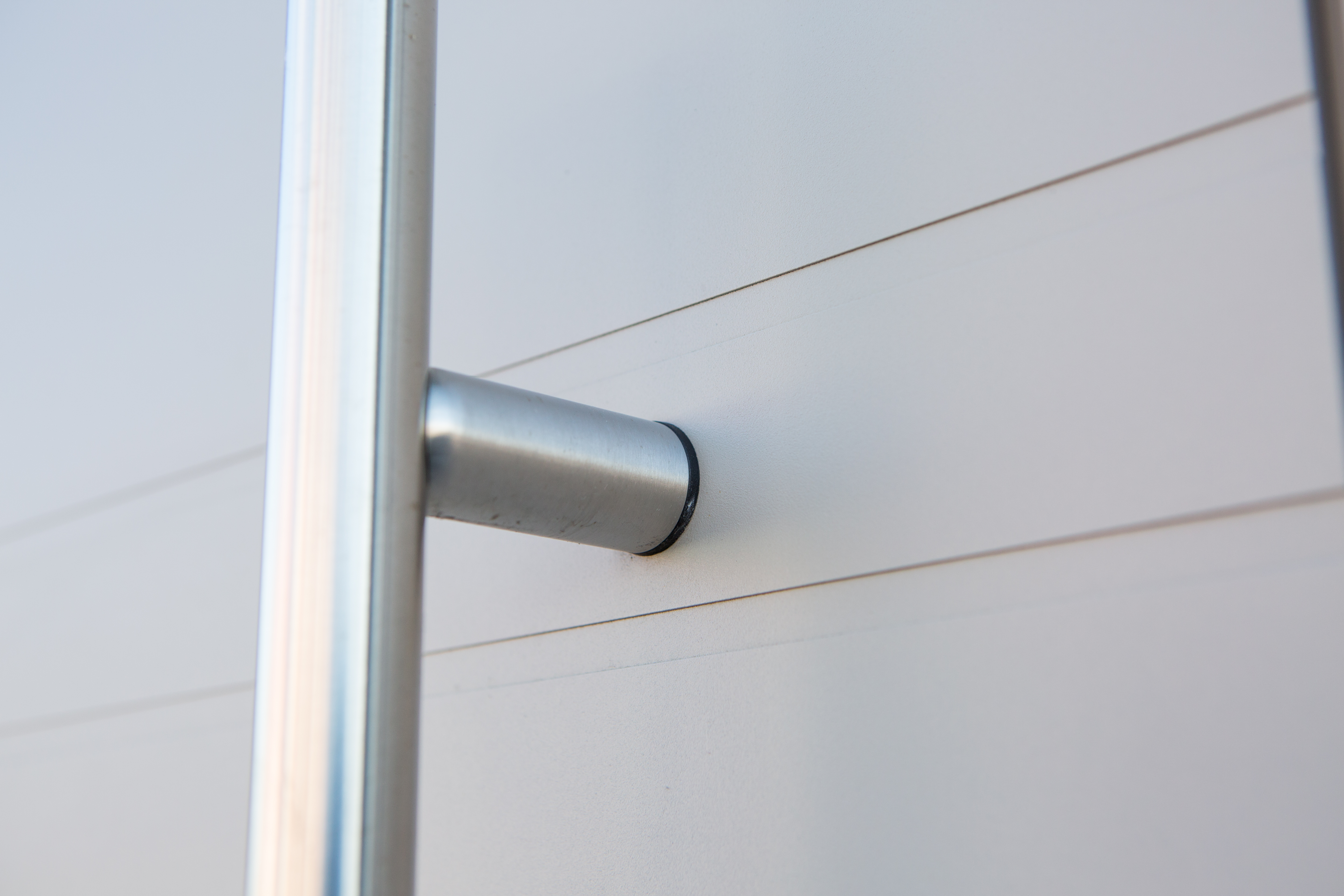 Close-up van een lichte, semi-beglazerde deur met zilverkleurige handgreep, in het kader van de renovatie van een driegevelwoning.