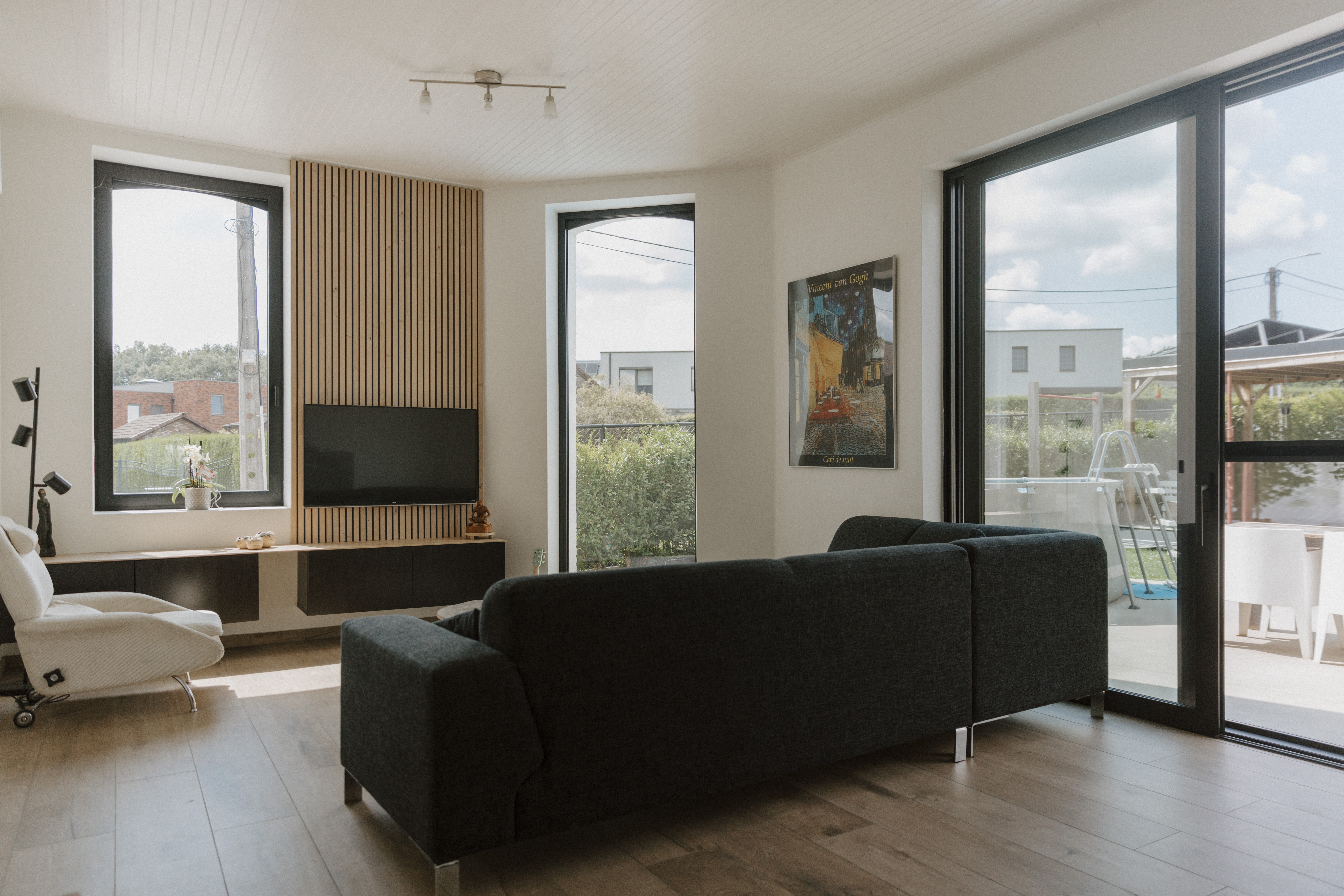Lichte woonkamer met diepzwarte aluminiumramen van Koncept: een vast raam, een draai-kipraam en een grote ALU Visoglide Monorail-schuifpui naar het terras.