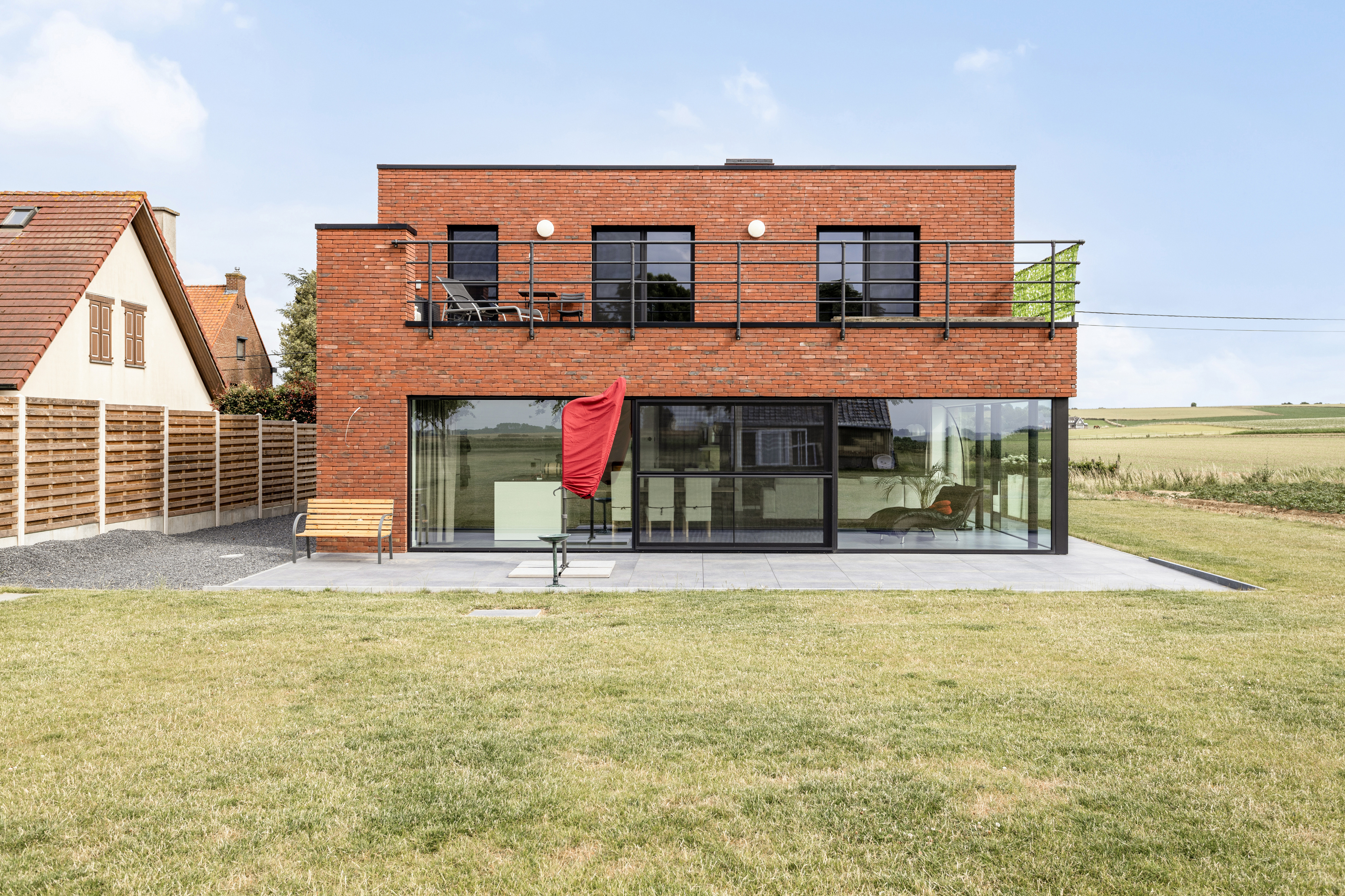 Moderne nieuwbouwwoning in open bebouwing met een groot vast raam in zwart 9005TC, gelegen in een open landelijke omgeving.