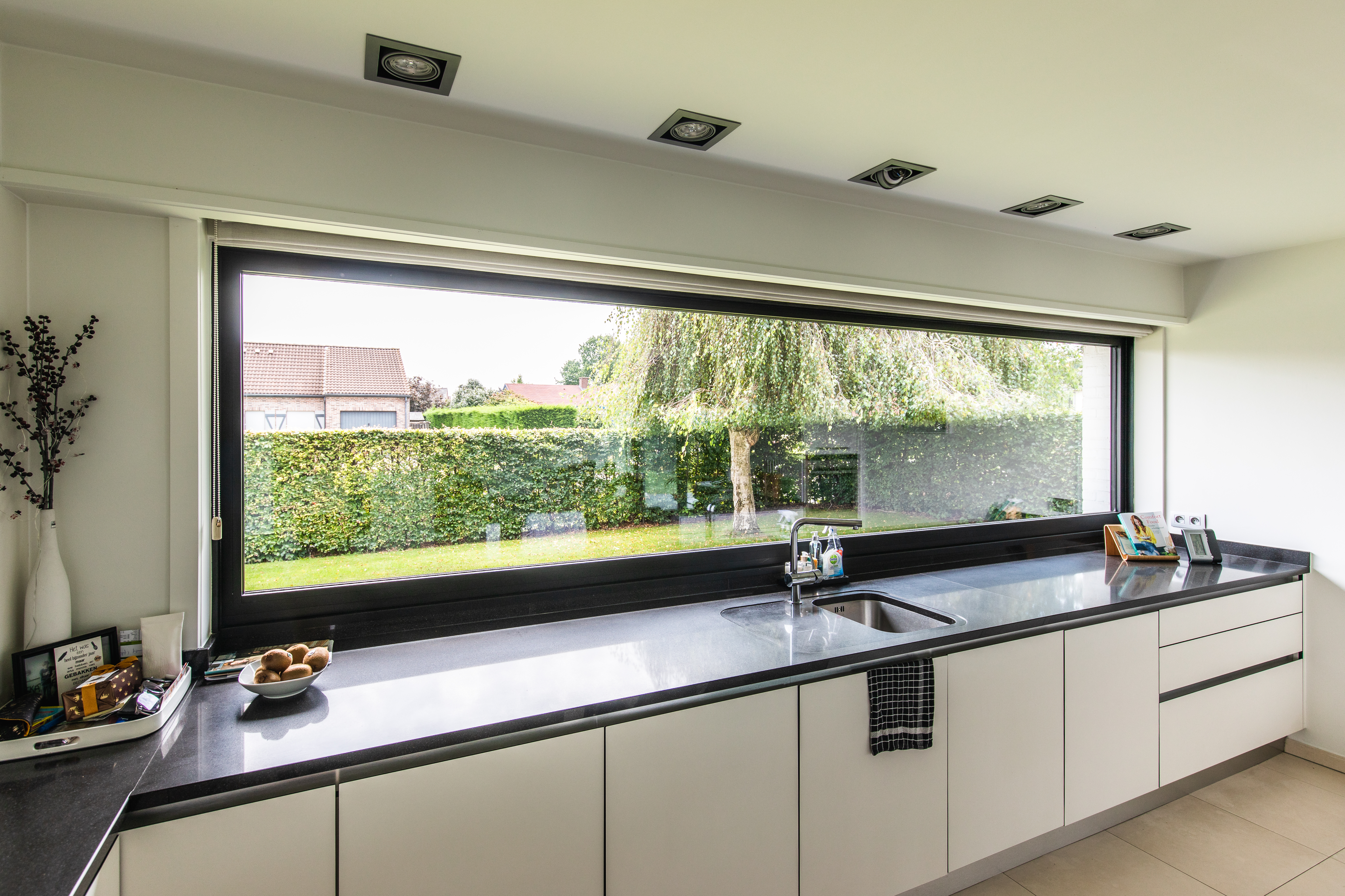 Karaktervol modern vast raam in 9005TC zwart boven een keukenwerkblad, met breed uitzicht op de tuin van een vrijstaande woning.