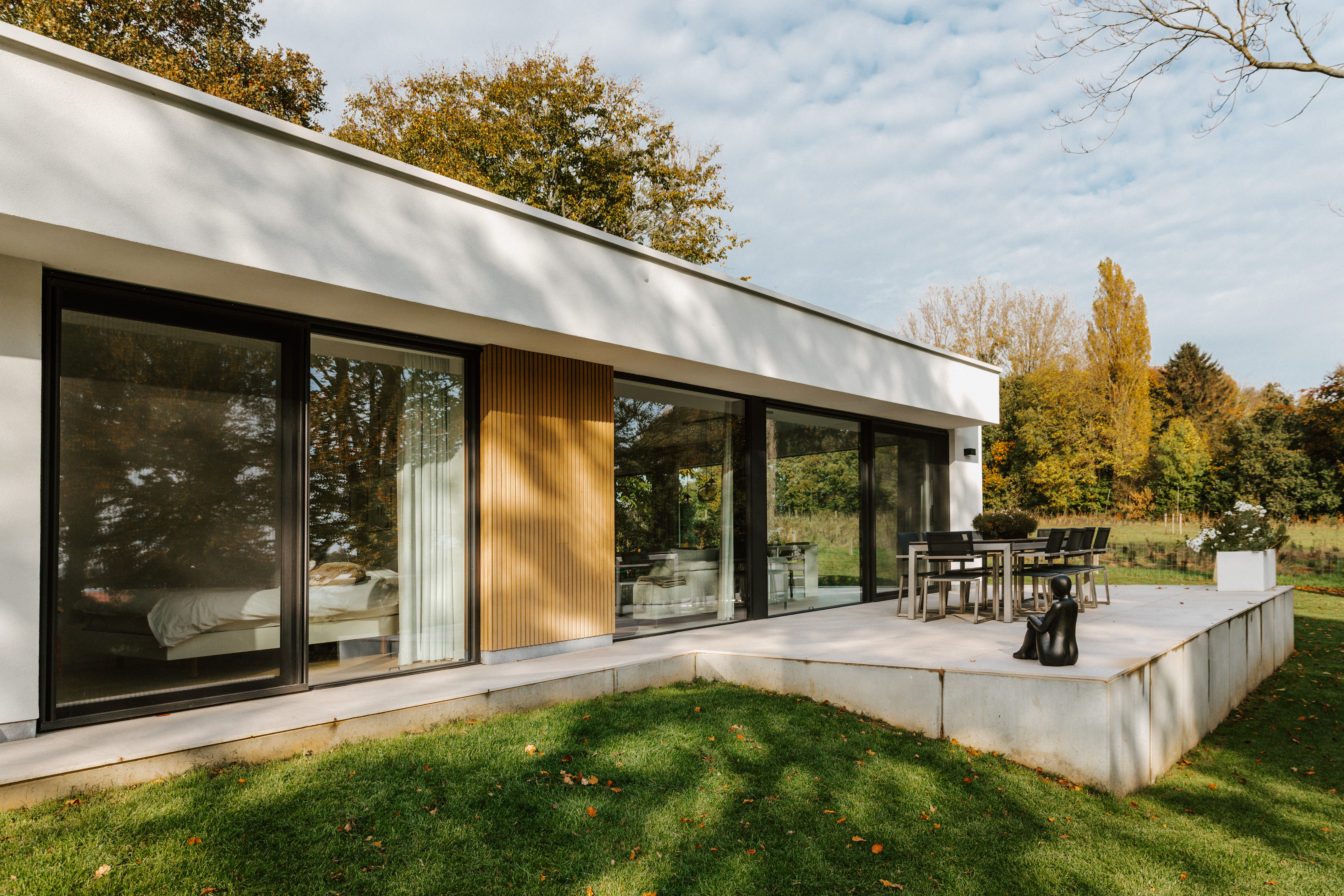 Moderne gerenoveerde vrijstaande woning met zwarte aluminium raamprofielen, een groot vast raam en een ALU Visoglide Monorail-schuifvliegenraam aan het terras.