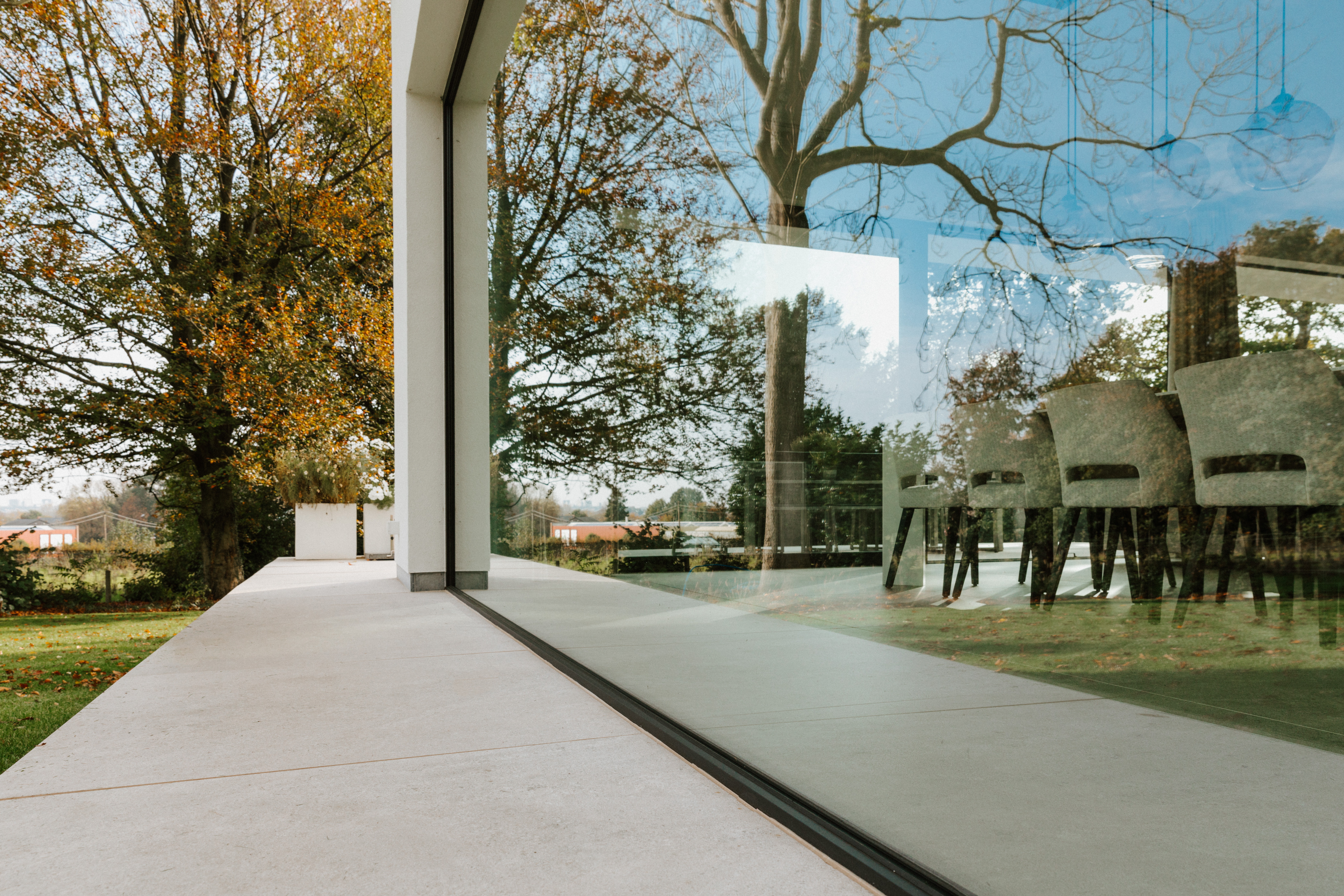 Groot vast raam met signaalzwarte raamprofielen in een moderne, gerenoveerde open bebouwing, met terras, tuin en eetruimte.