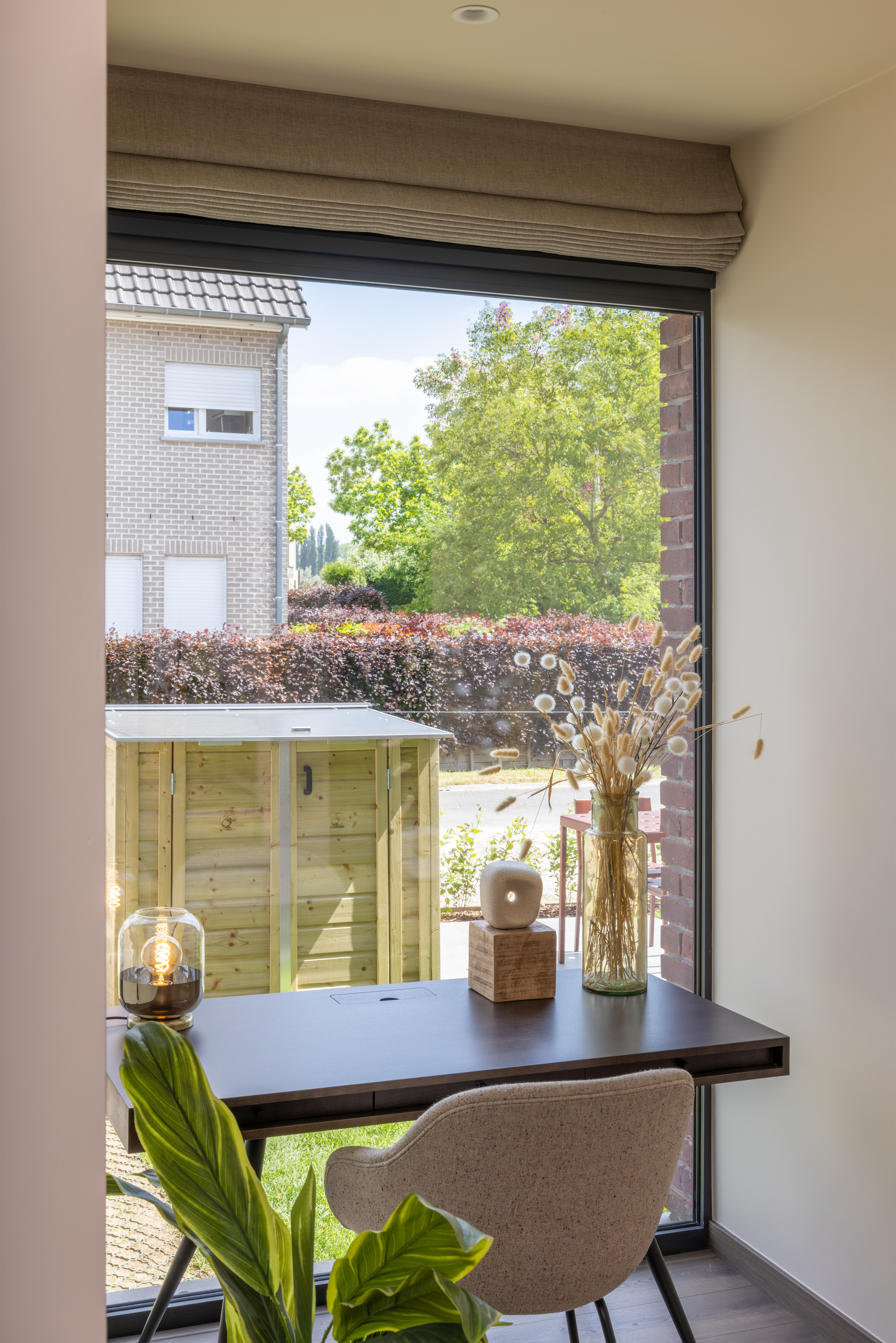 Anthracietgrijs vast raam in een gerenoveerde gesloten bebouwing met een gemoedelijke, tijdloze uitstraling en uitzicht op de tuin en omliggende woningen.