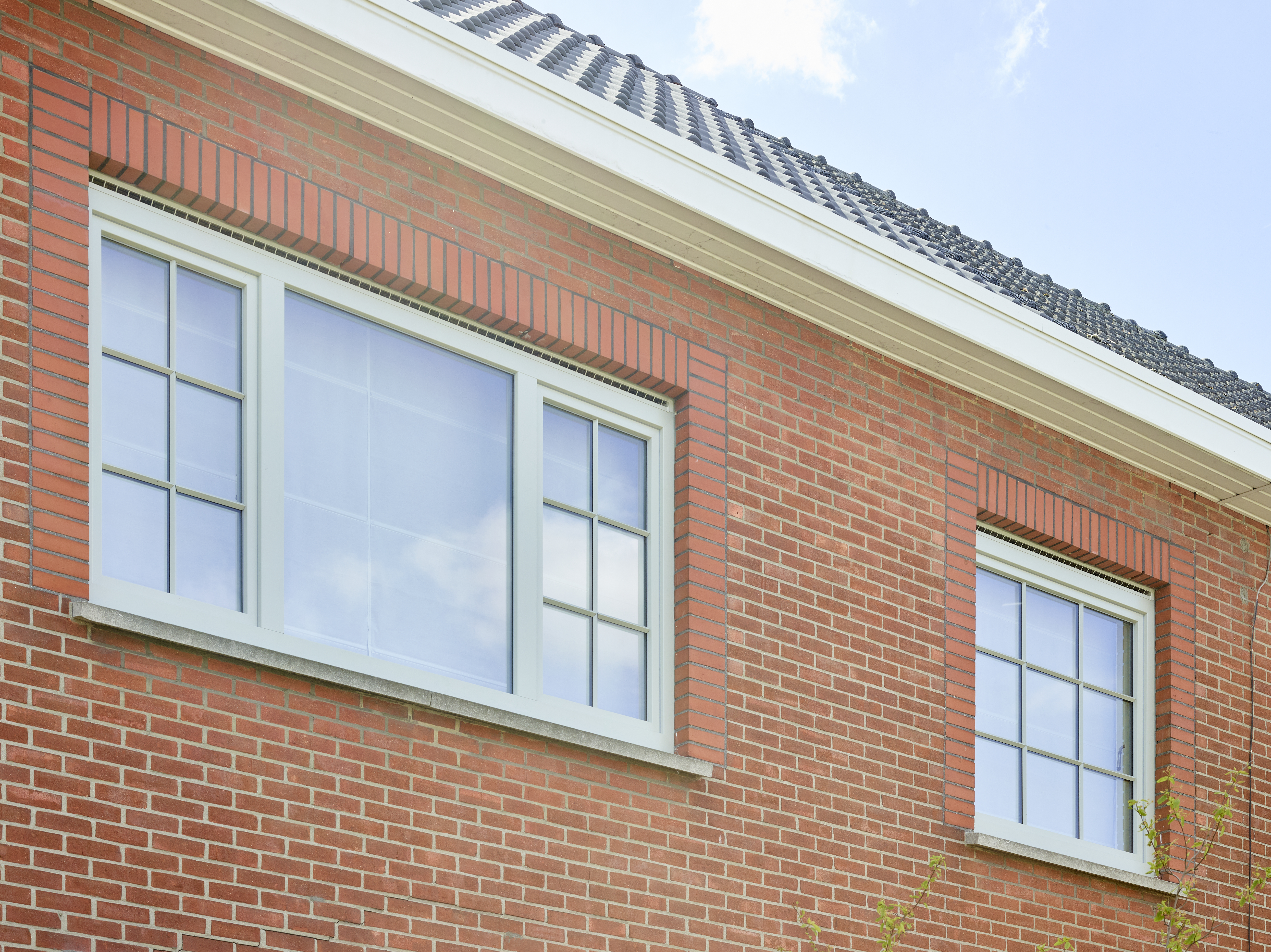 Roodbakstenen gevel met agaatgrijze steellook draai-kipramen en een raam met driedubbele beglazing in een warme, landelijke stijl.