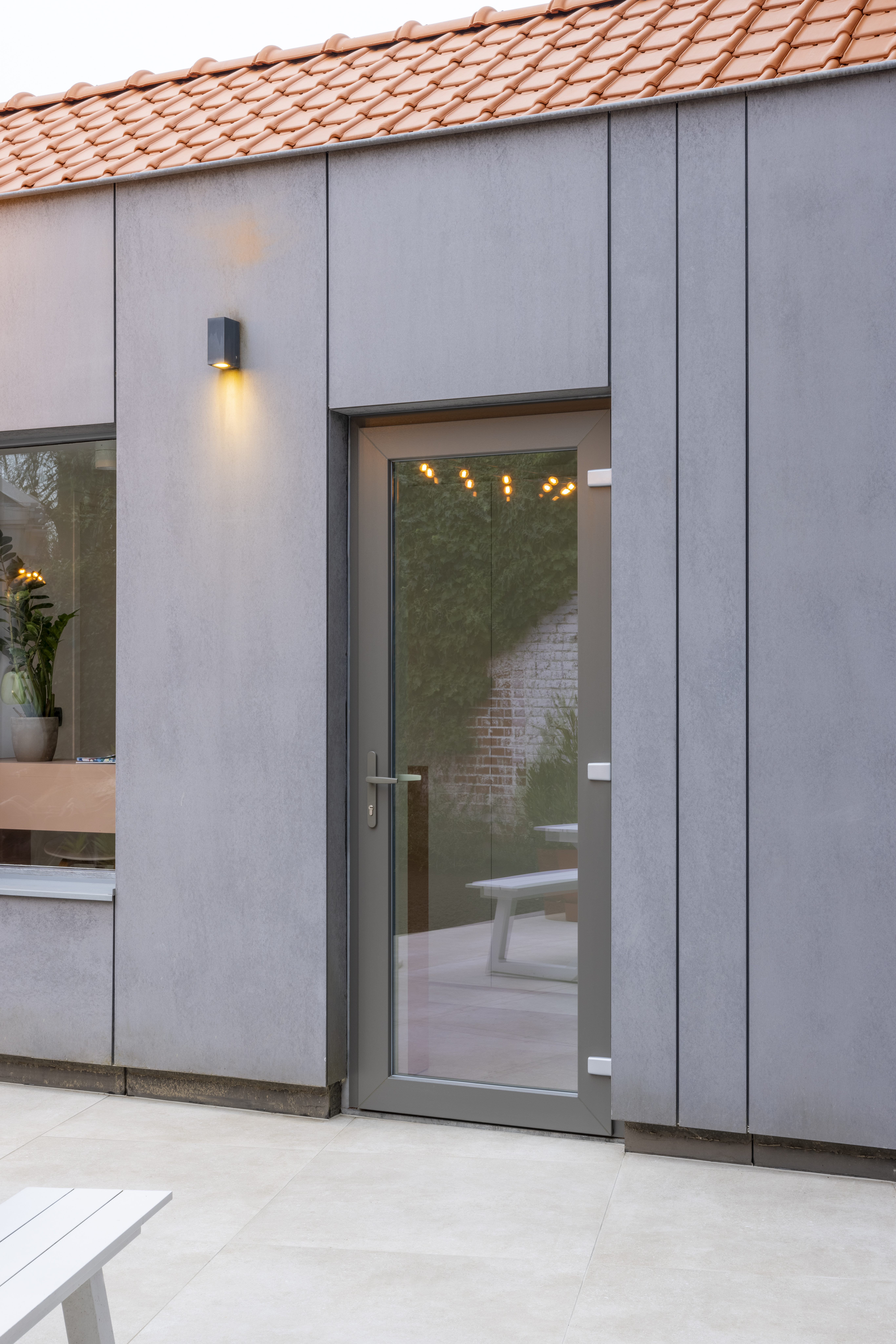 Moderne, gerenoveerde gevel in gesloten bebouwing met een beglaasde deur in kwartsgrijze PVC Impakt PLUS-profielen.
