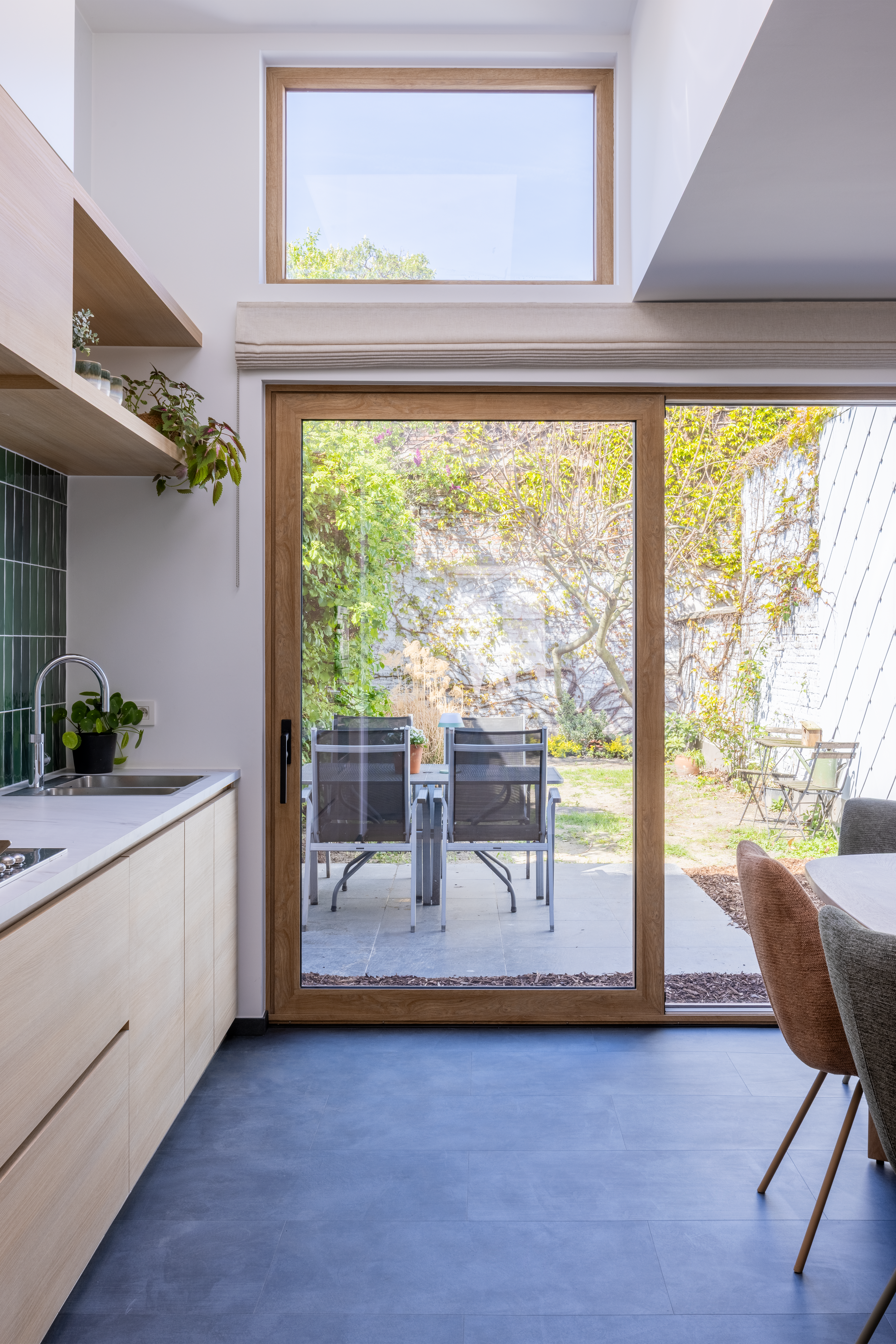 Gerenoveerde keuken met een groot aluminium schuifraam in decor Natuur Eik en een vast raam erboven met uitzicht op de tuin.