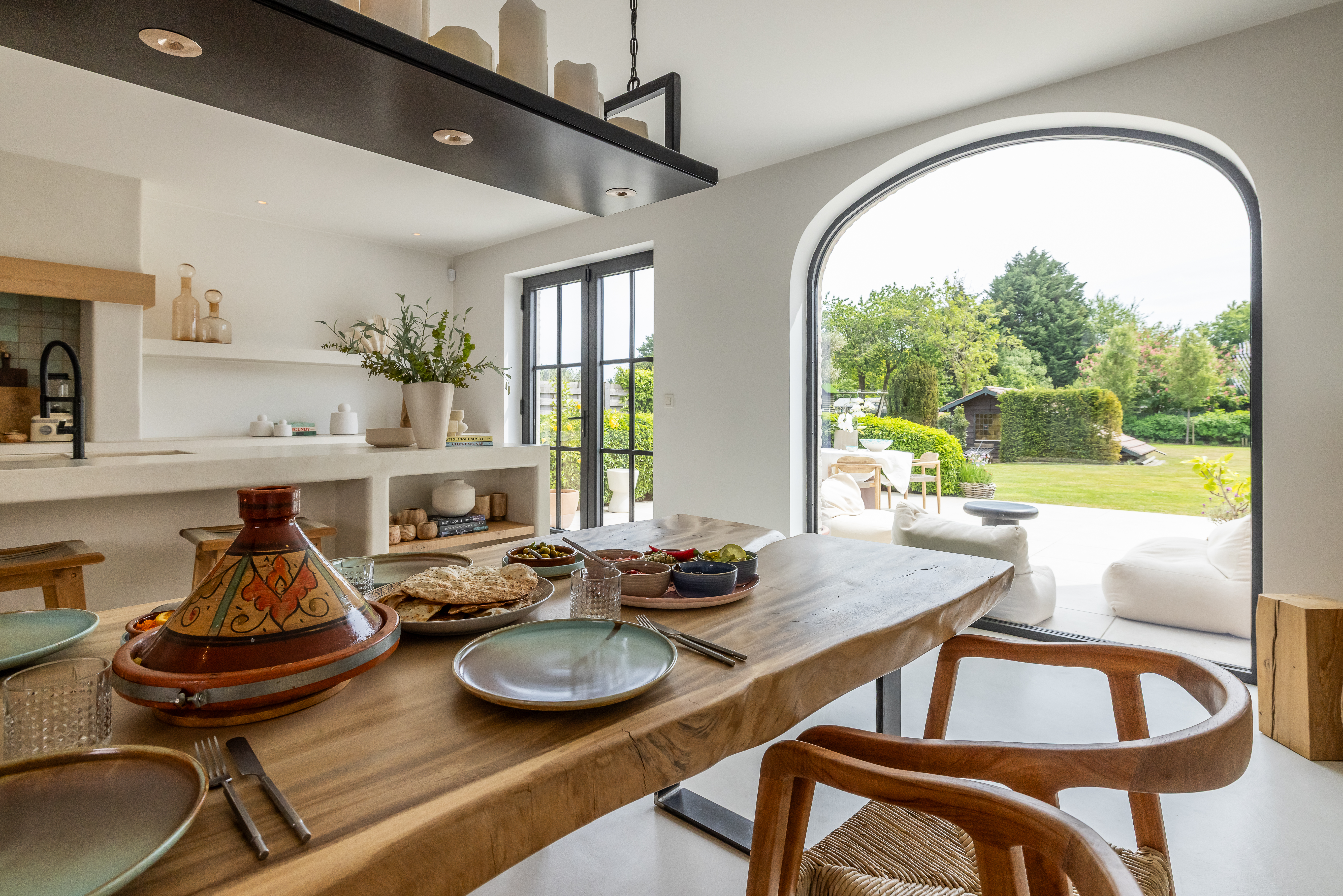 Groot vast Steellook PLUS small-raam met slanke zwarte profielen en rondboog, in een warm landelijk interieur van een nieuwbouwwoning met zicht op de tuin.