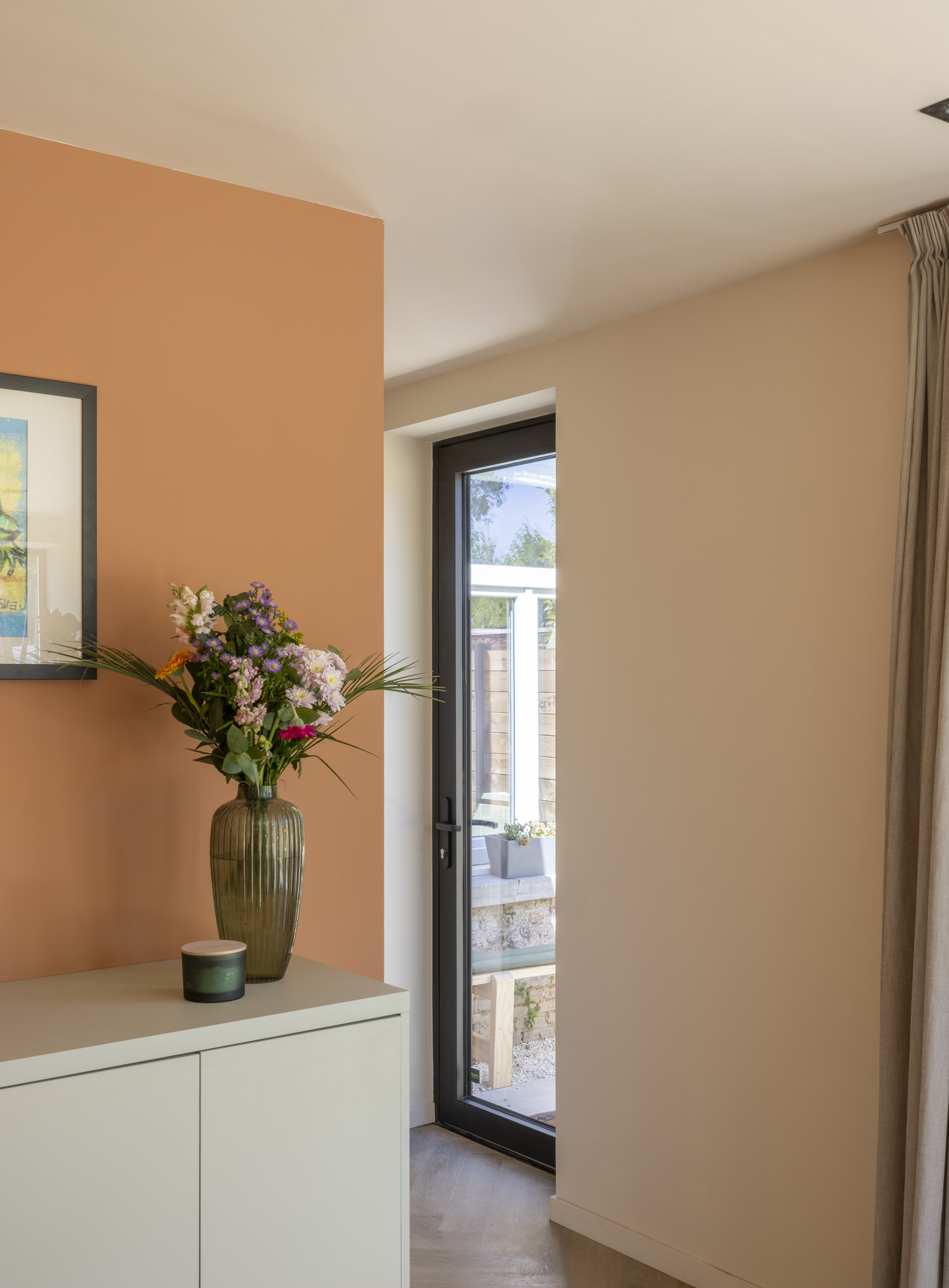 Een zwarte beglaasde aluminiumdeur uit de ALU Komfort EVO-reeks geeft in een warm interieur uit op een buitenruimte met balustrade.