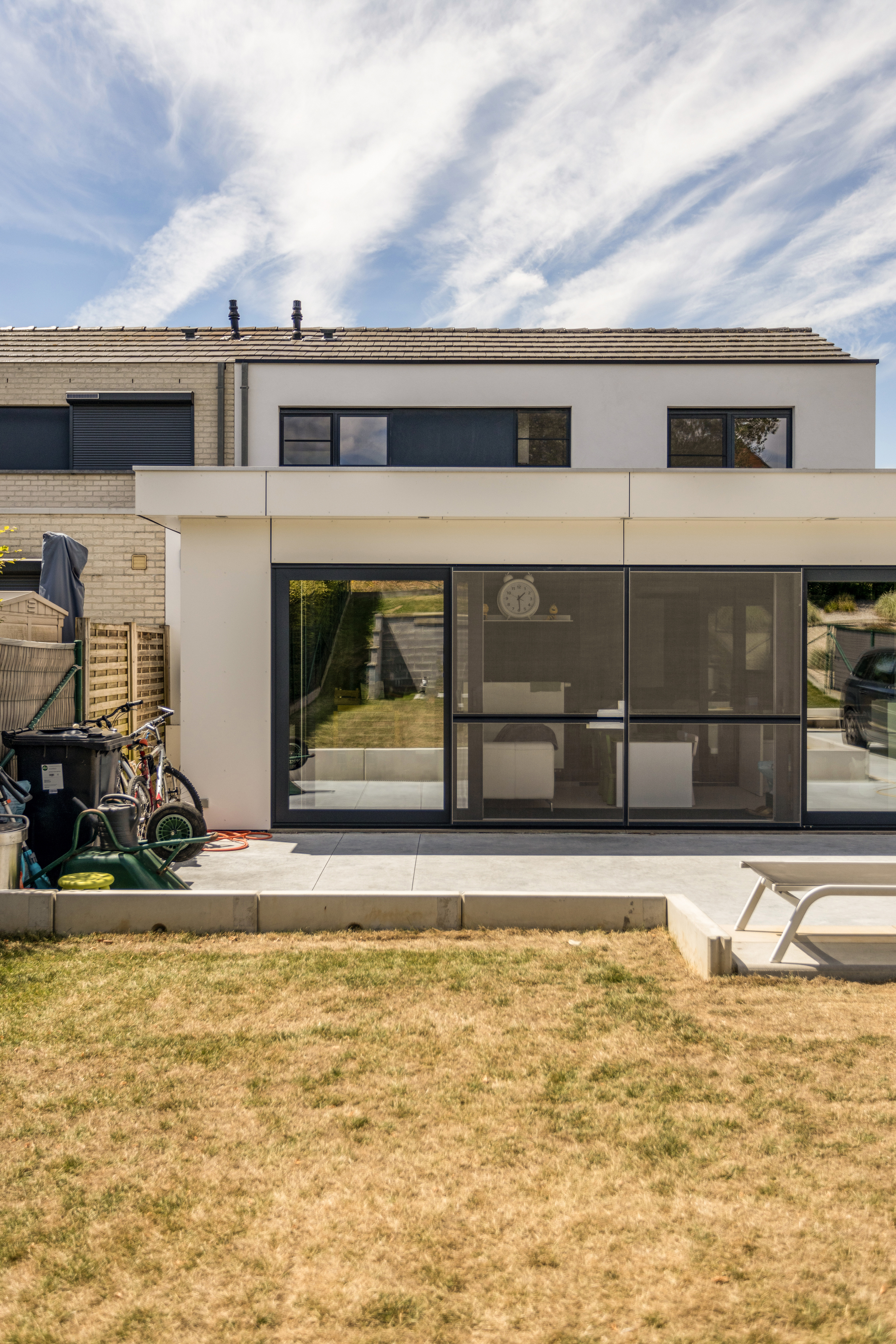 Moderne woning met een groot zwart ALU Visoglide Duorail-schuifvliegenraam aan de tuinzijde.