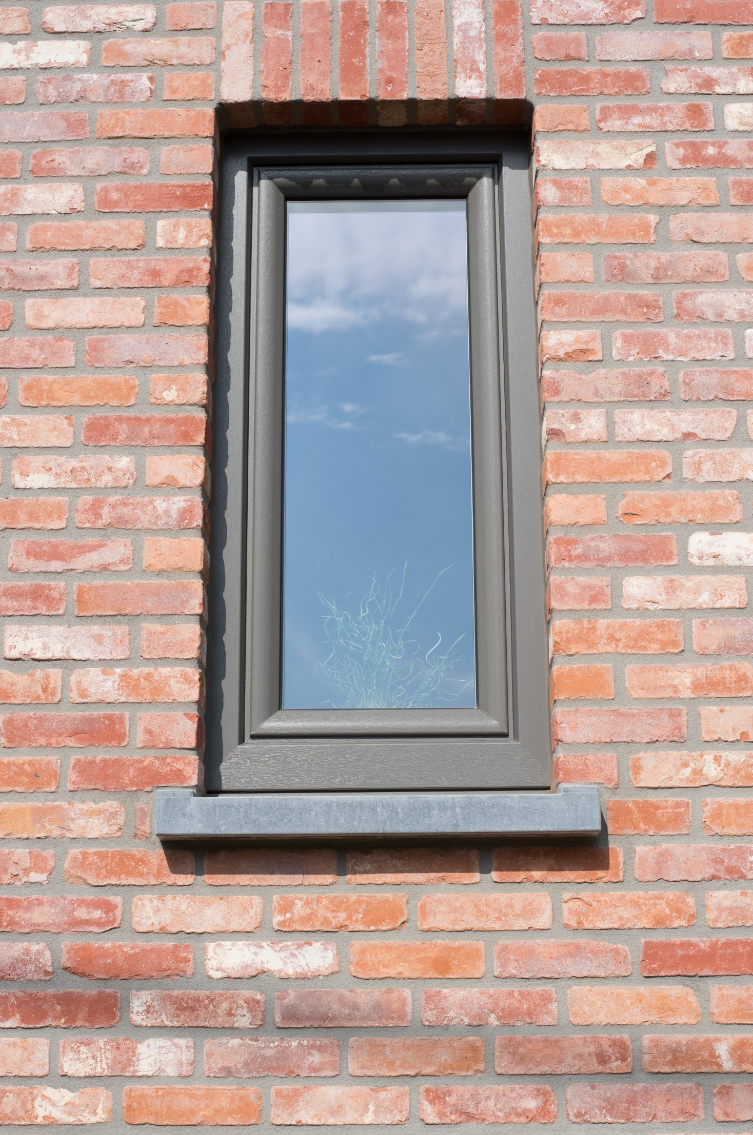 Kwartsgrijs draai-kipraam met NERF-afwerking in een bakstenen gevel van een tijdloze nieuwbouwwoning.