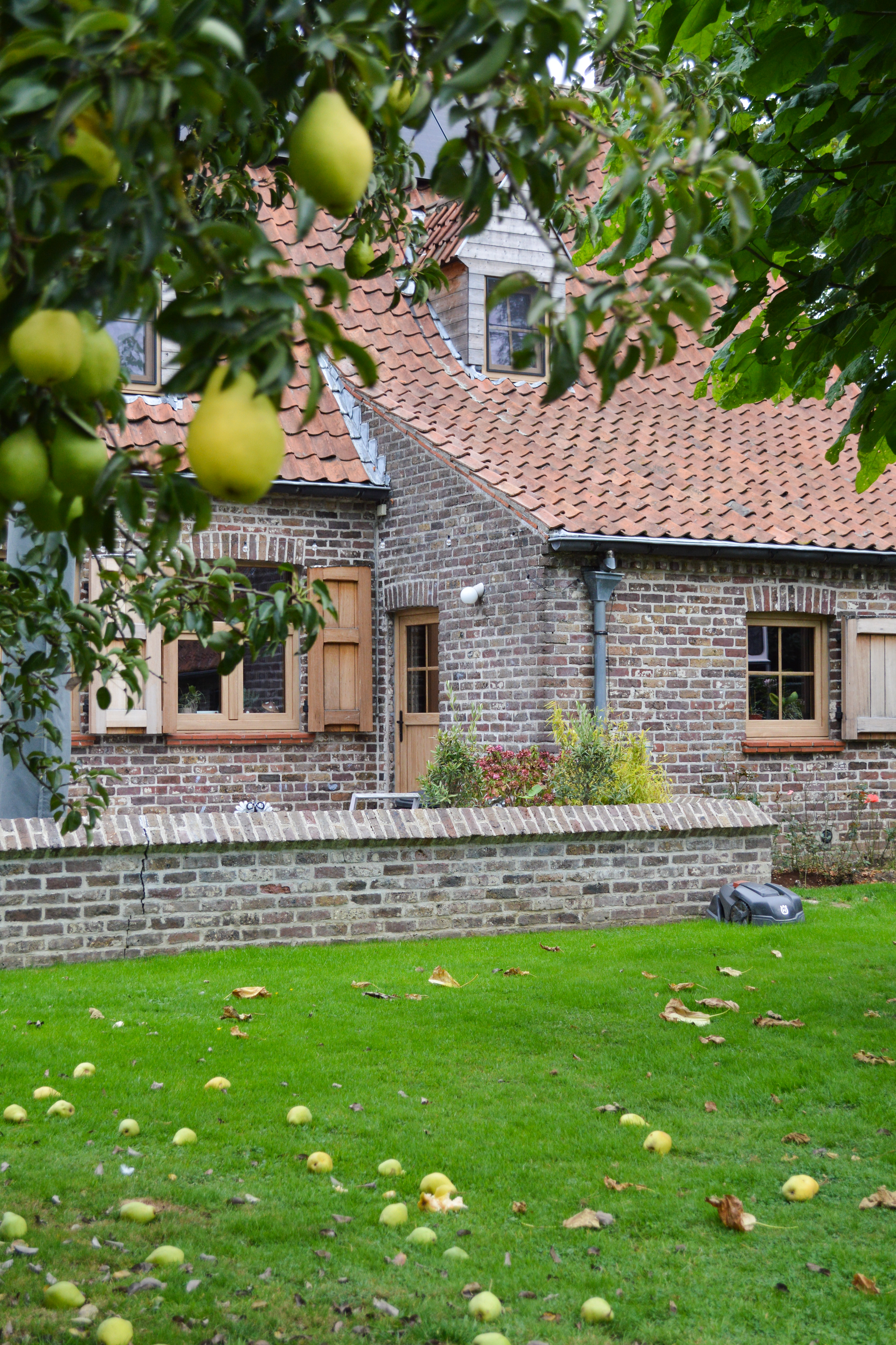 Bakstenen woning met rood pannendak en meerdere dubbele draai-kiepramen in natuurlijke eiklook, met een recht Impakt PLUS-profiel.