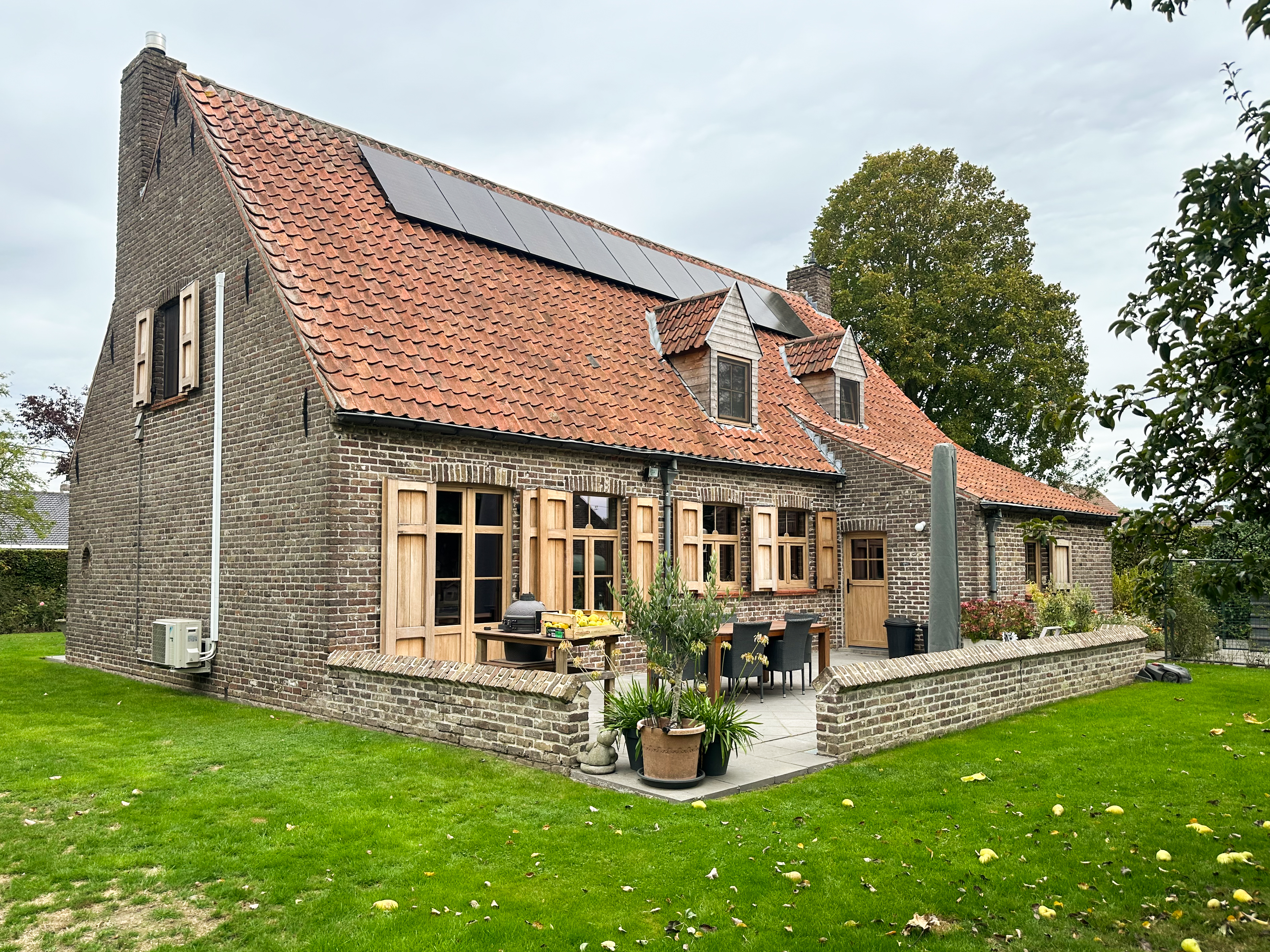 Bakstenen woning met pvc-ramen in natuurlijke eiklook, waaronder dubbele ramen, draai-kipramen en een raam met bovenlicht, plus een semi-beglaasde deur.