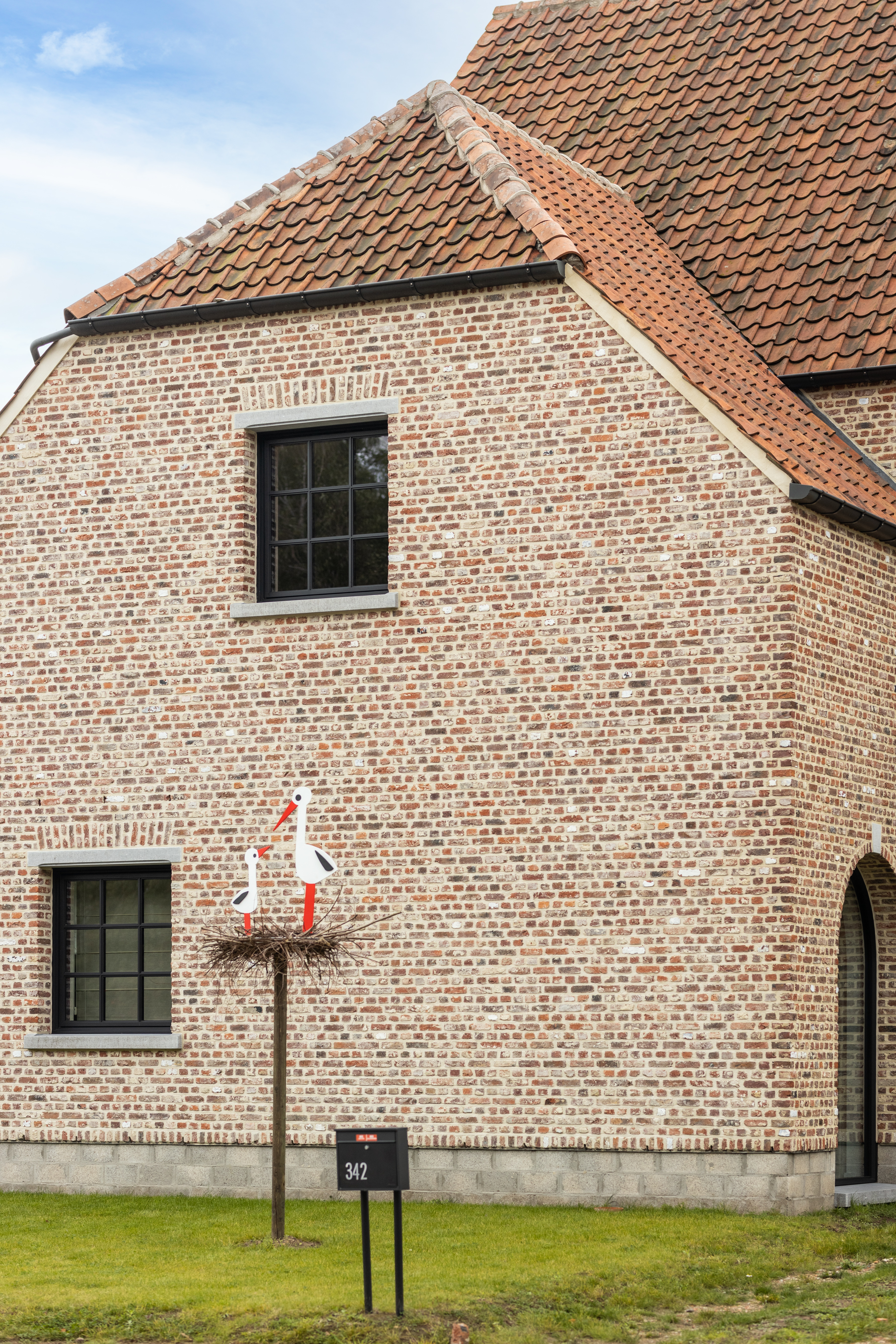 Zwart Steellook PLUS small draai-kipraam in de warme, landelijke bakstenen gevel van een vrijstaande woning.