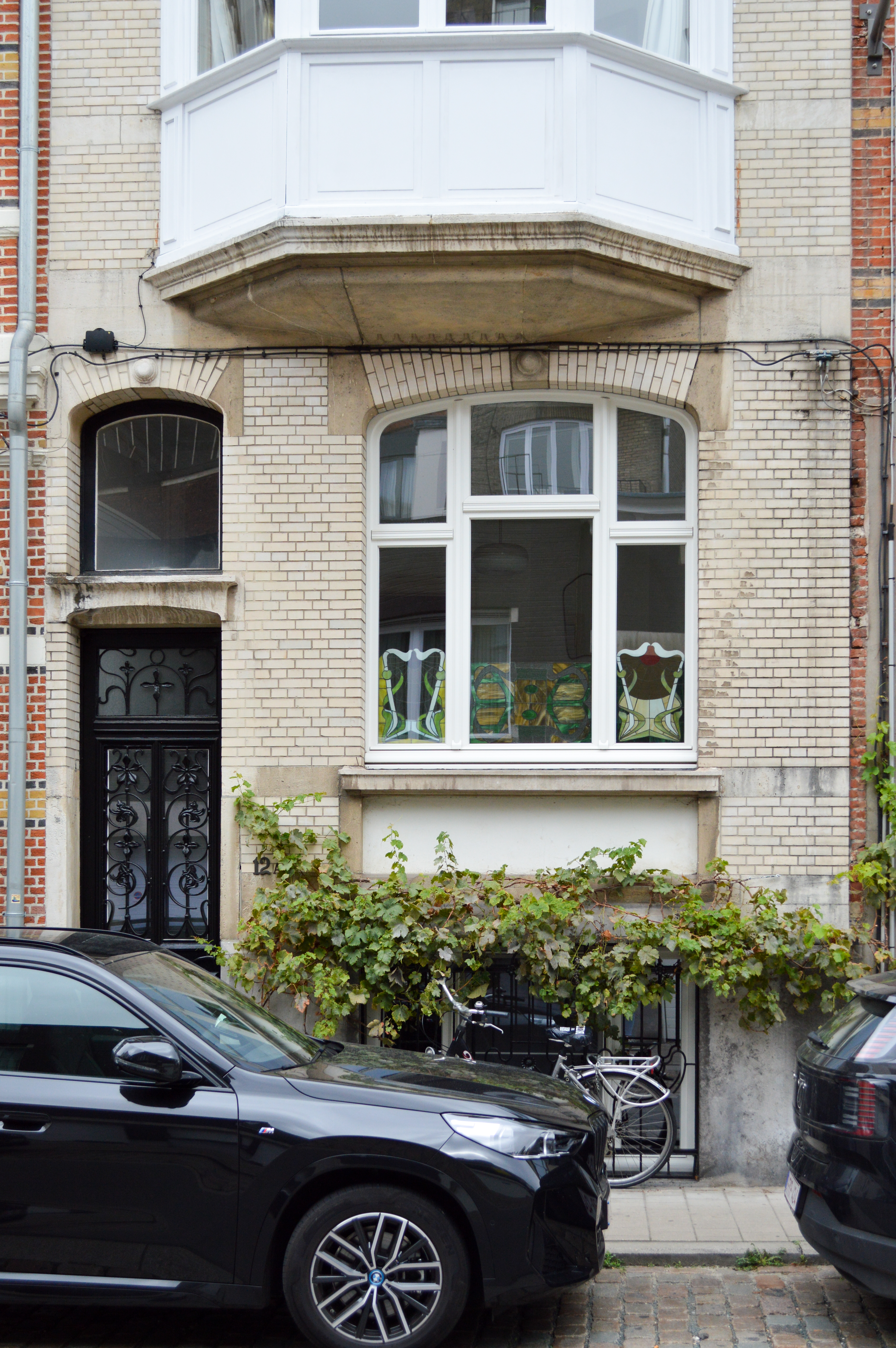 Gerenoveerde gevel in gesloten bebouwing met wit afgelakte, verfijnd klassieke raamcombinatie: een draai-kipraam, raam met bovenlicht en vast raam.