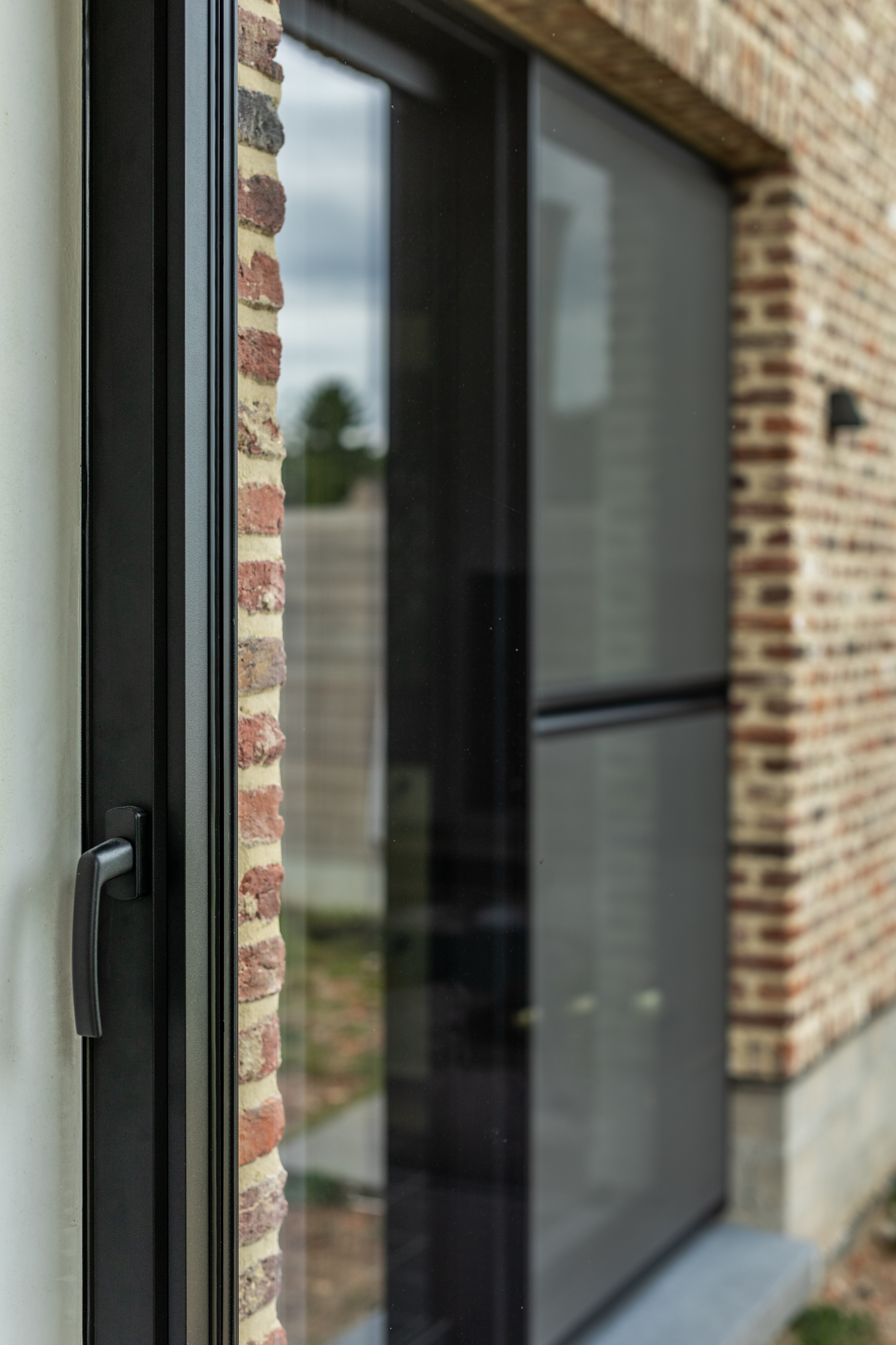 Zwart Steellook PLUS-raamprofiel met grote glasvlakken in een warme bakstenen gevel van een landelijke nieuwbouwwoning.