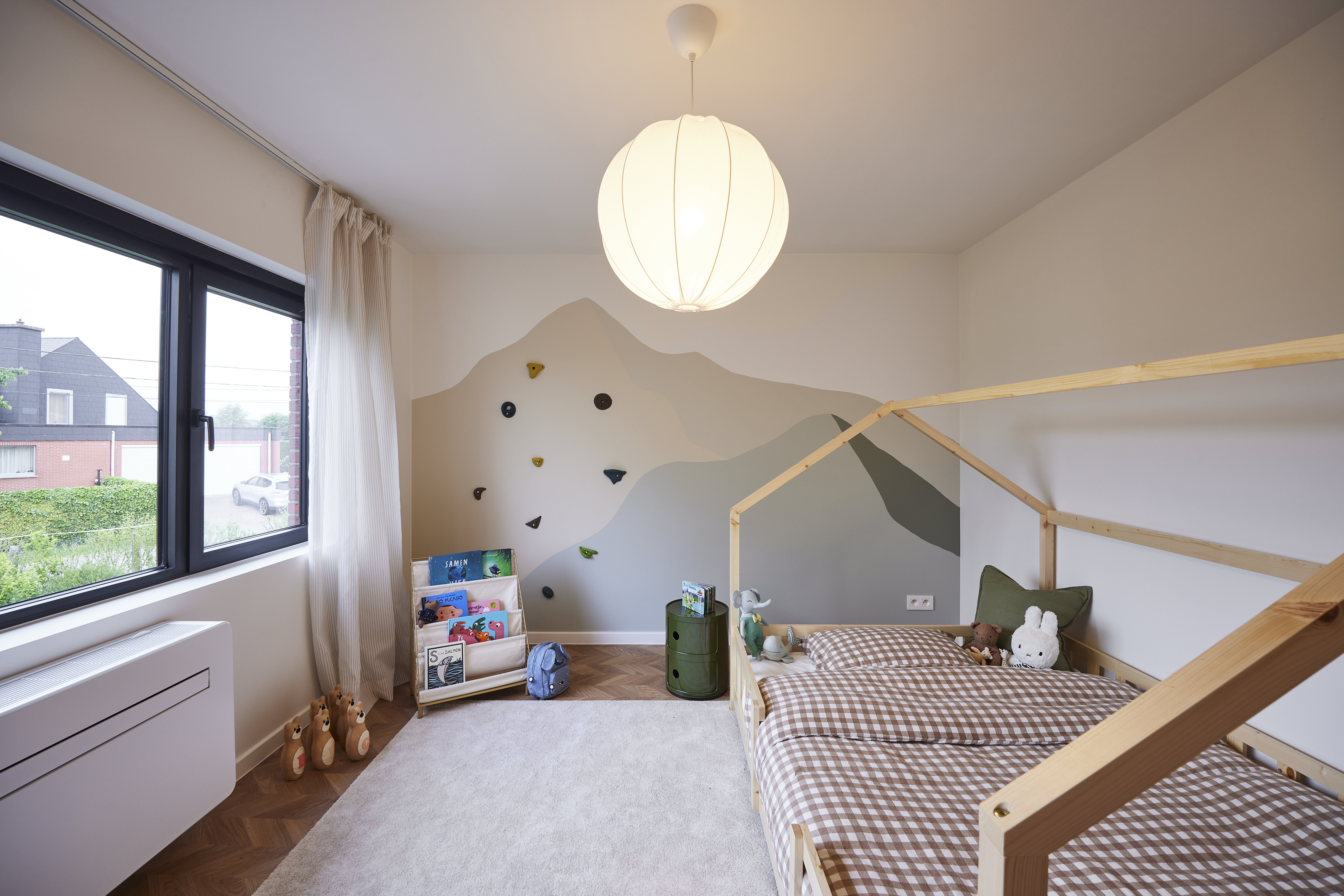 Kinderkamer met een grafietzwart Komfort EVO small-raam, uitgevoerd als combinatie van vast raam, dubbel raam en draai-kipraam, naast een bed.