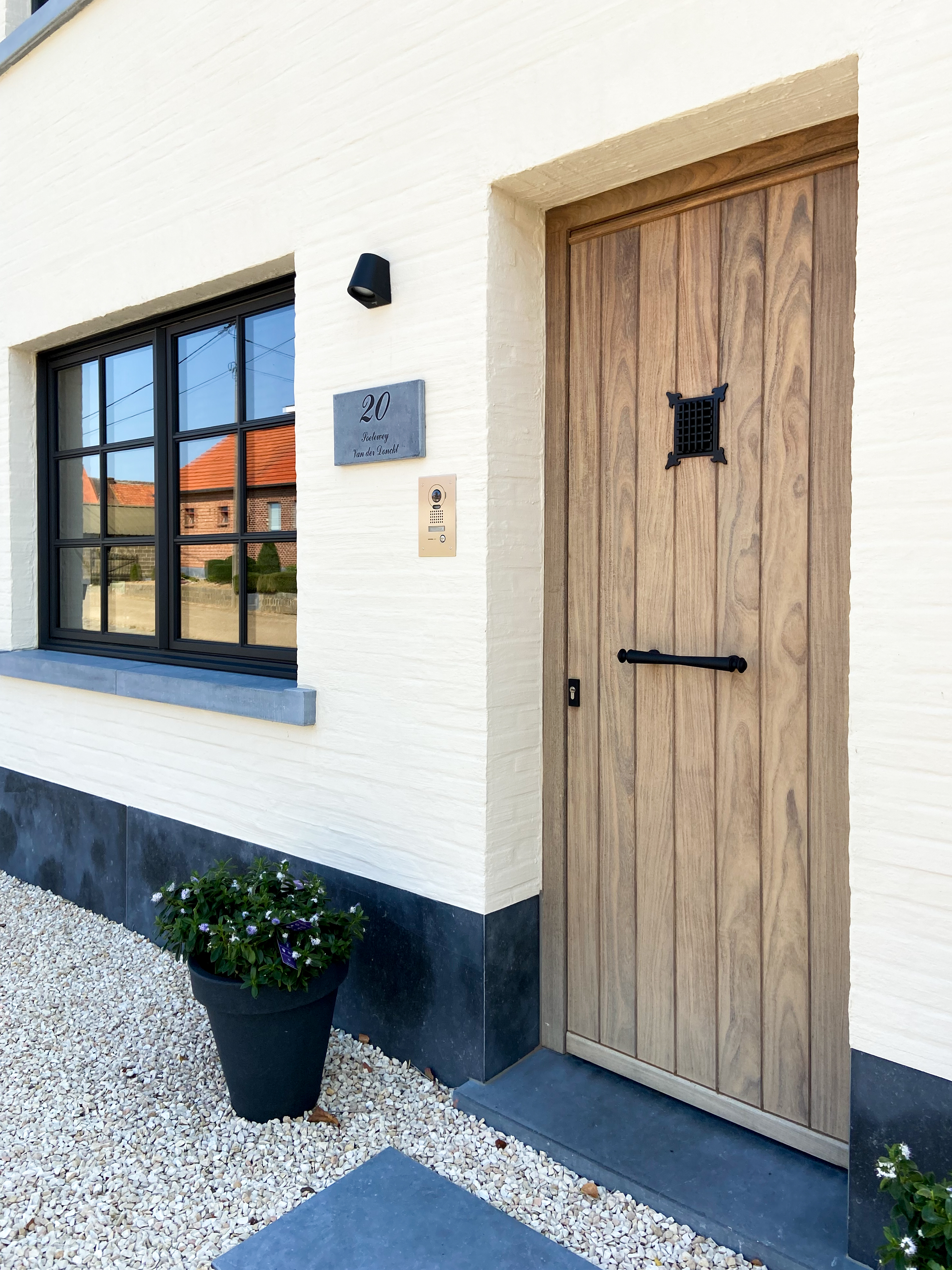 Gerenoveerde vrijstaande woning met een zwart 9005TC Steellook PLUS Small dubbel draai-kipraam naast een houten paneeldeur in warme landelijke stijl.