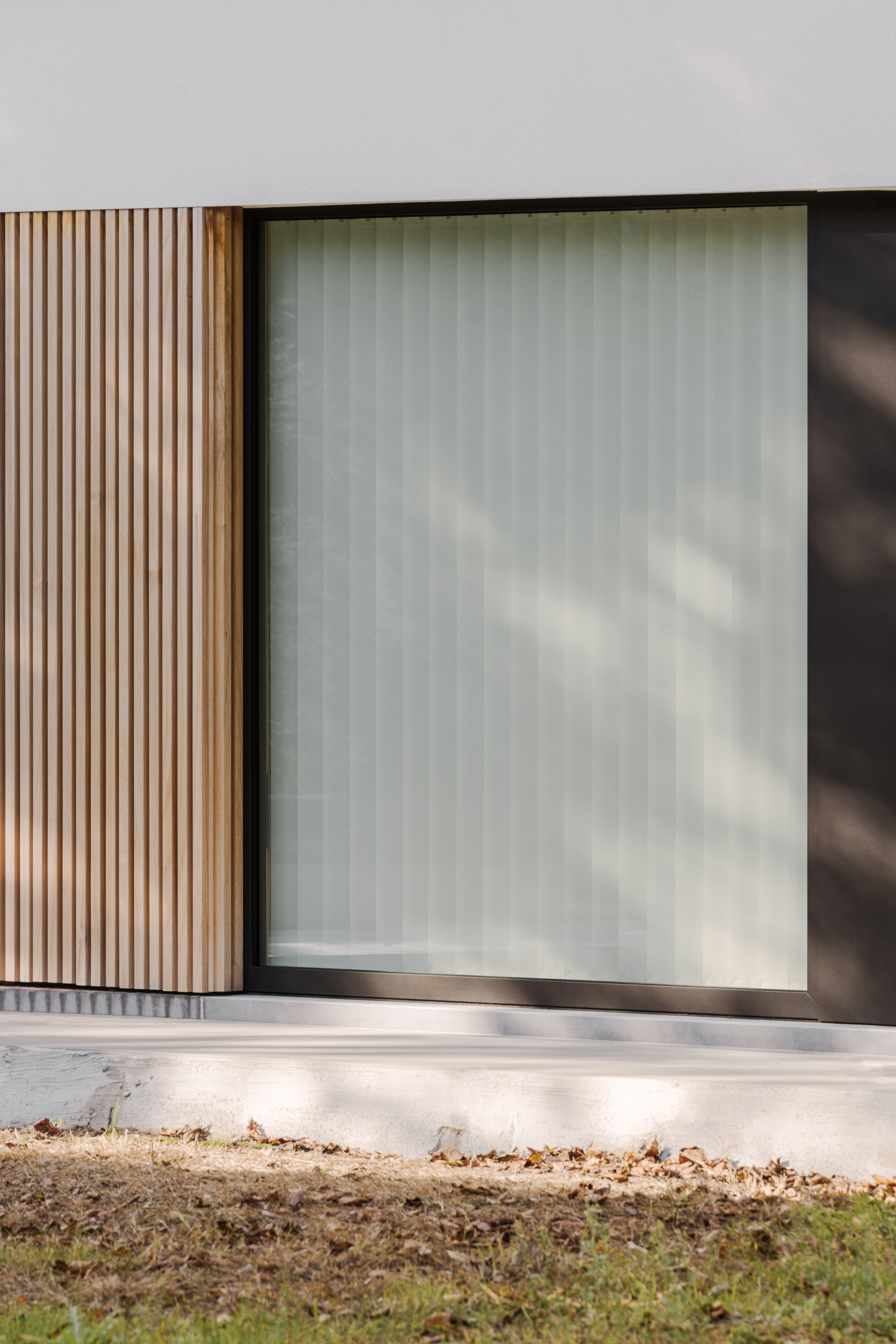 Modern vast raam met zwart 9005TC-raamprofiel, geïntegreerd in een gevel van een nieuwbouwwoning met verticale houten bekleding.