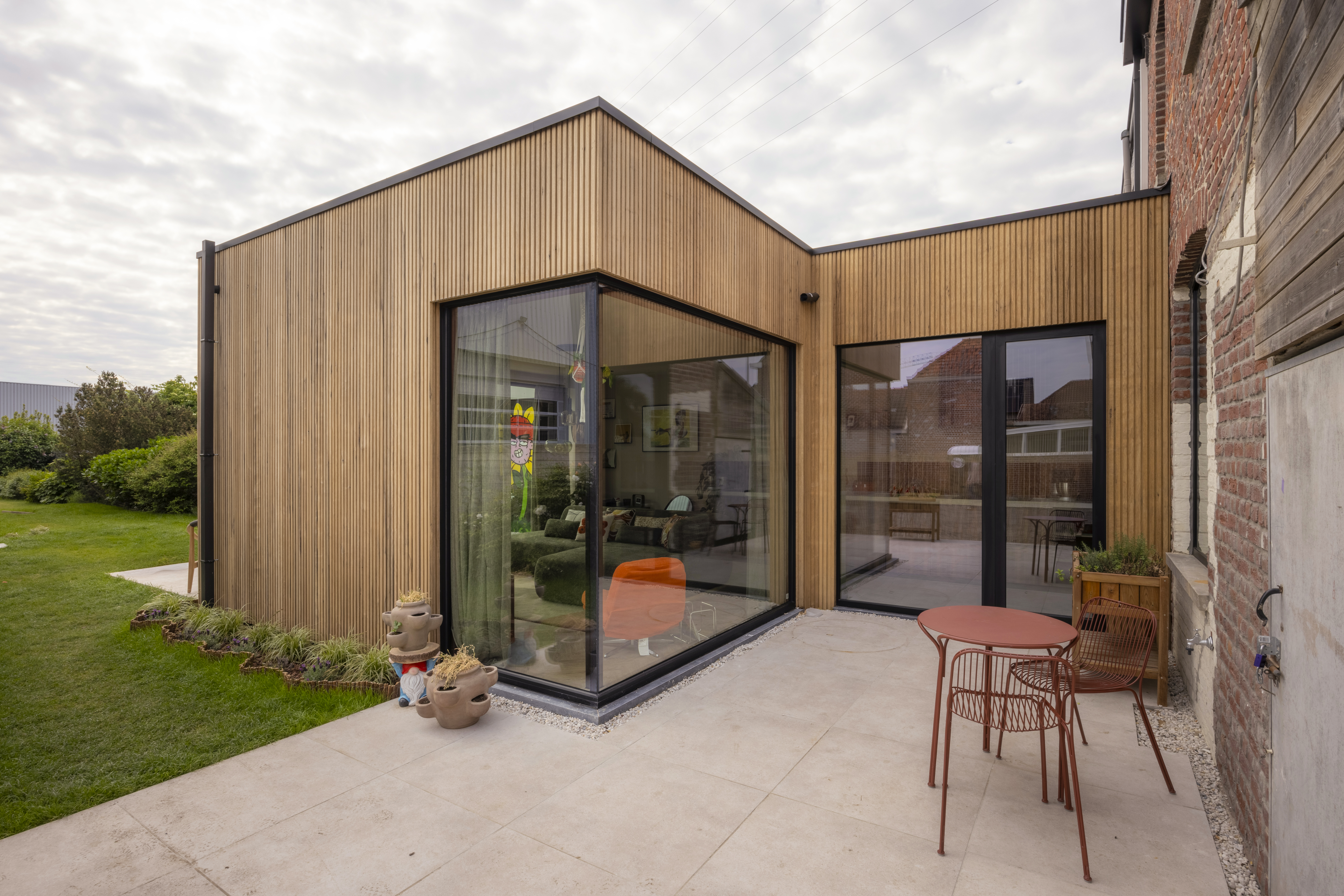 Houten aanbouw met diepzwarte Komfort EVO small raamprofielen, een vast raam en een draai-kipraam aan het terras.